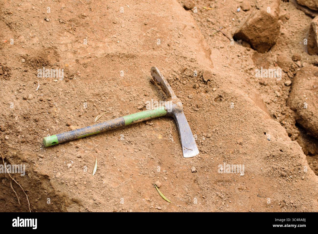 Ein kleines Pickaxe-Werkzeug auf dem Boden an einer Ausgrabungsstelle. Konzept das wesentliche Instrument der Entdeckung. Stockfoto