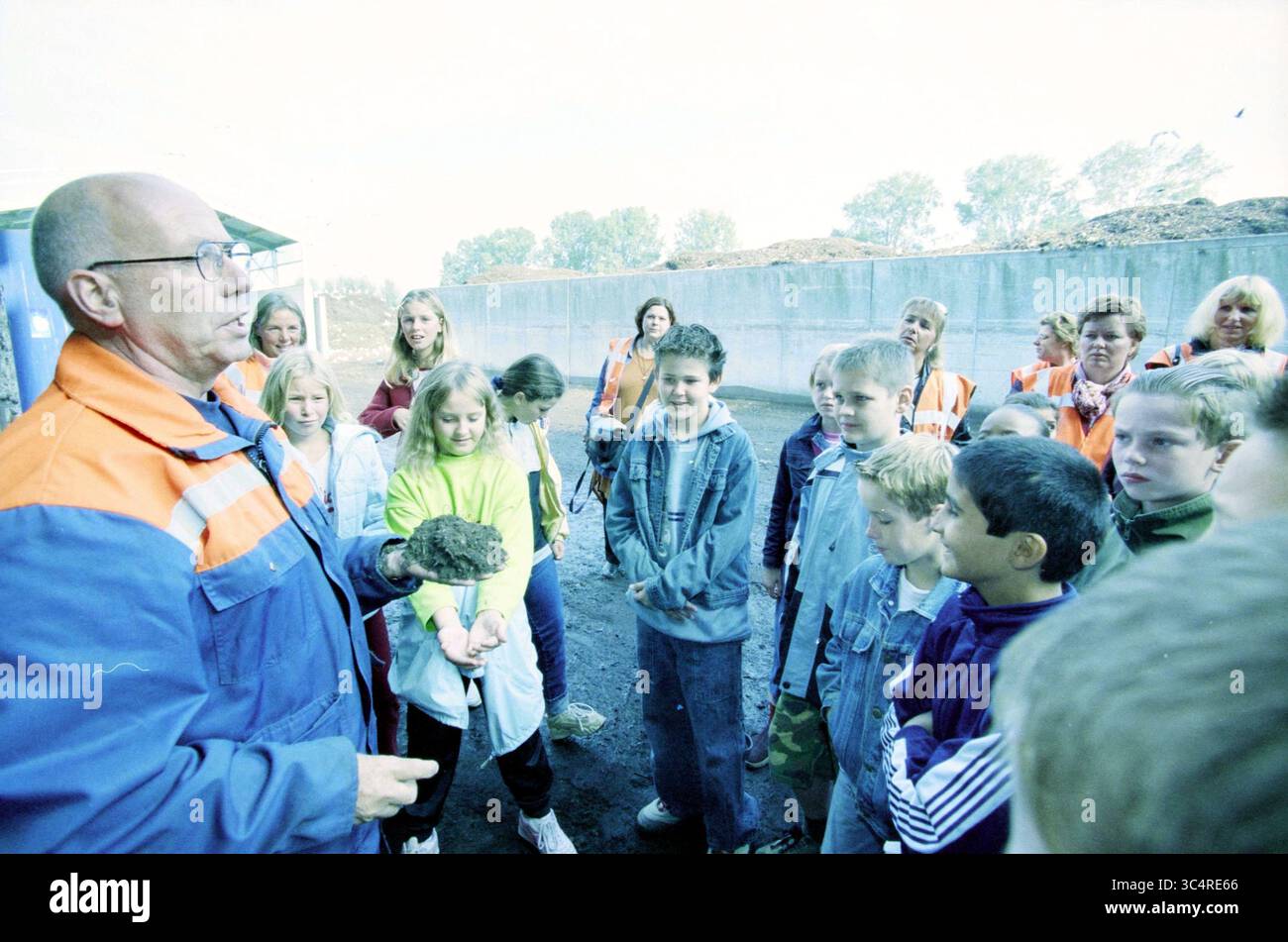 De Meerlanden, Rijsenhout, Rijsenhout, 01-10-2003 Whizgle News, Dutch Desk, Niederlande, 1950-2000 Eine Gruppe von Kindern hört aufmerksam einem Erwachsenen zu, der etwas in der Hand zeigt, das wahrscheinlich mit Boden- oder Umweltwissenschaften in Verbindung steht. Die Teilnehmer sind in verschiedenen farbenfrohen Jacken gekleidet, und die Umgebung scheint ein Outdoor-Ausflug zu sein, bei dem Erwachsene die Gruppe beaufsichtigen. Stockfoto