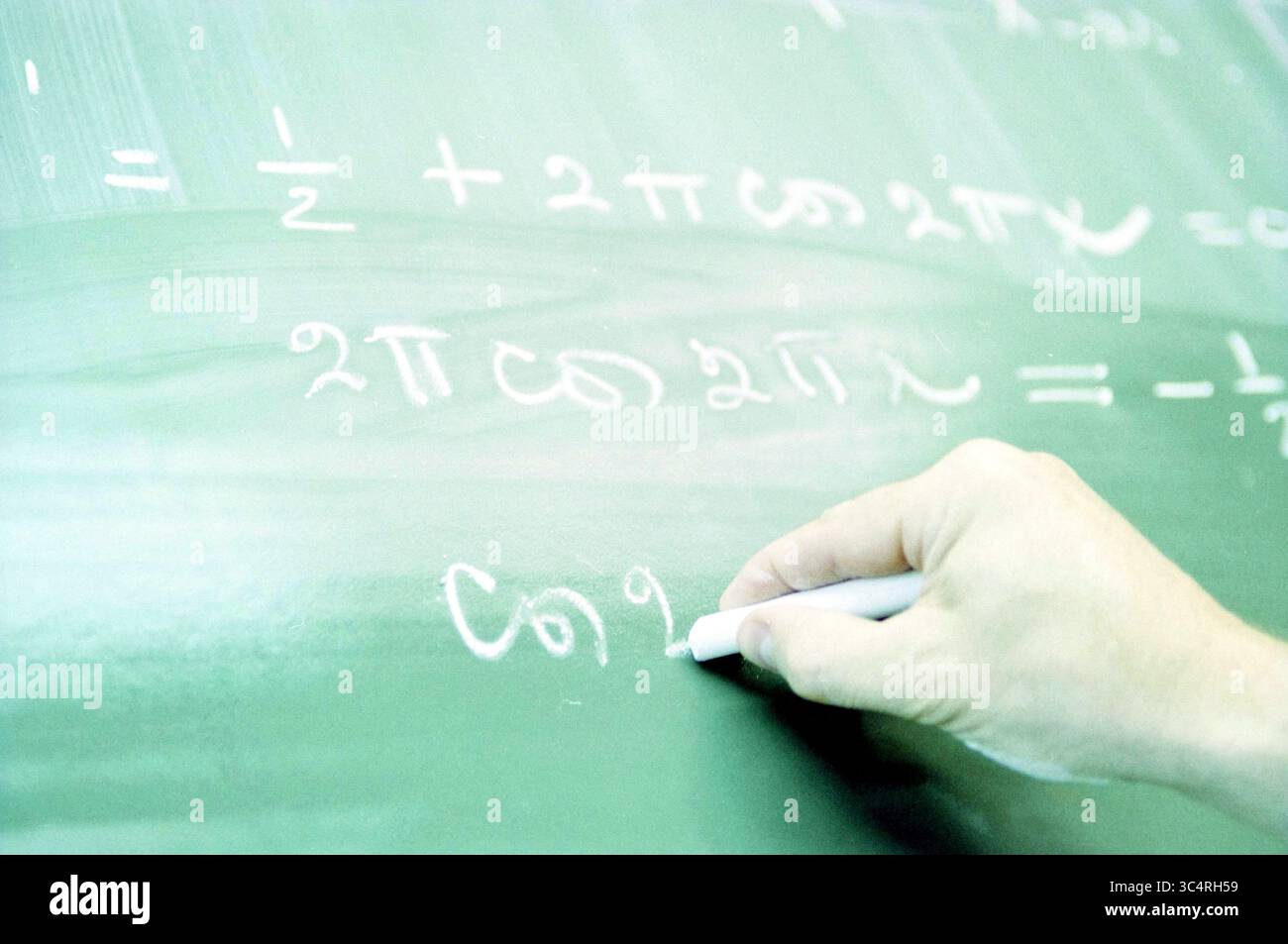 Exams, Mathe, 15-05-2000 Whizgle News, Dutch Desk, Niederlande, 1950-2000 Eine Hand schreibt mathematische Gleichungen auf ein grünes Tafel mit Symbolen und Formeln, die Brüche und trigonometrische Funktionen enthalten. Stockfoto
