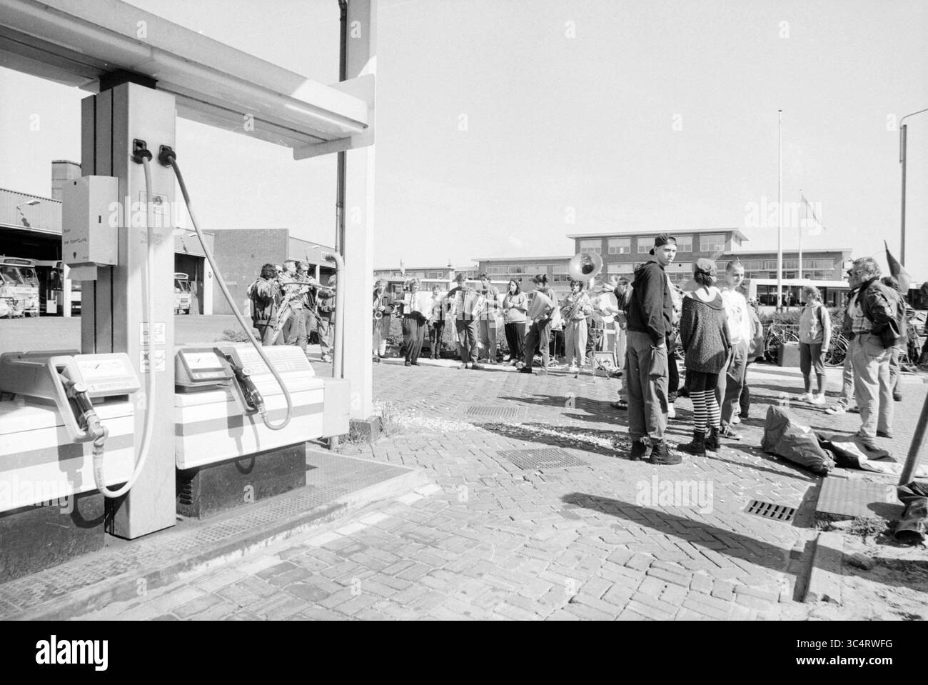 Protest gegen die Apartheid in Südafrika an einer Shell-Pumpe. Whizgle News, Dutch Desk, Niederlande, 1950-2000 In der Nähe einer Tankstelle versammelt sich Eine geschäftige Menschenmenge, in der sich mehrere Leute unterhalten, während andere in der Schlange nach Treibstoff warten. Die Szene reflektiert einen Moment der Aktivität und Interaktion in einer geschäftigen städtischen Umgebung. Stockfoto