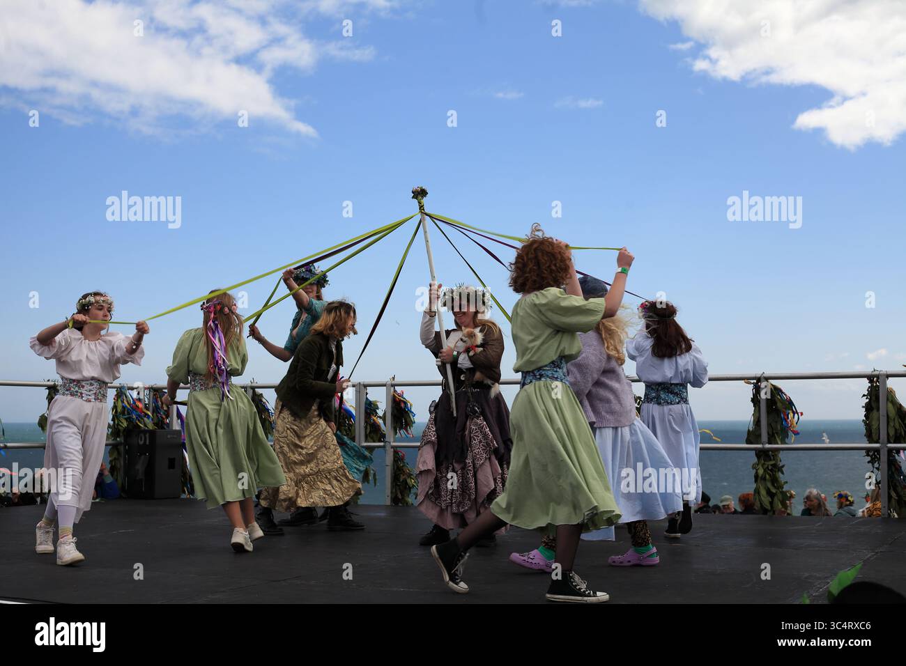 Maypole-Tänzer, die Bänder um einen zentralen Stab auf der Bühne weben, Jack in the Green, Hastings, Großbritannien Stockfoto