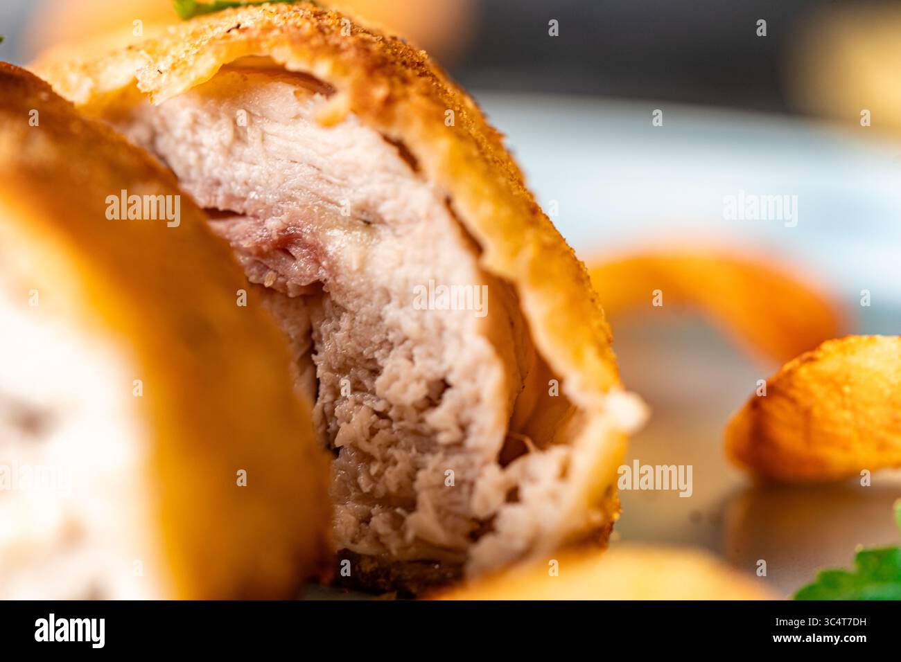 Hühnchen gefüllt mit Speck und Käse, gebraten in Lision. Ein traditionelles französisches Gericht Cordon bleu auf einem blauen Teller. Nahaufnahme. Hochwertige Fotos Stockfoto