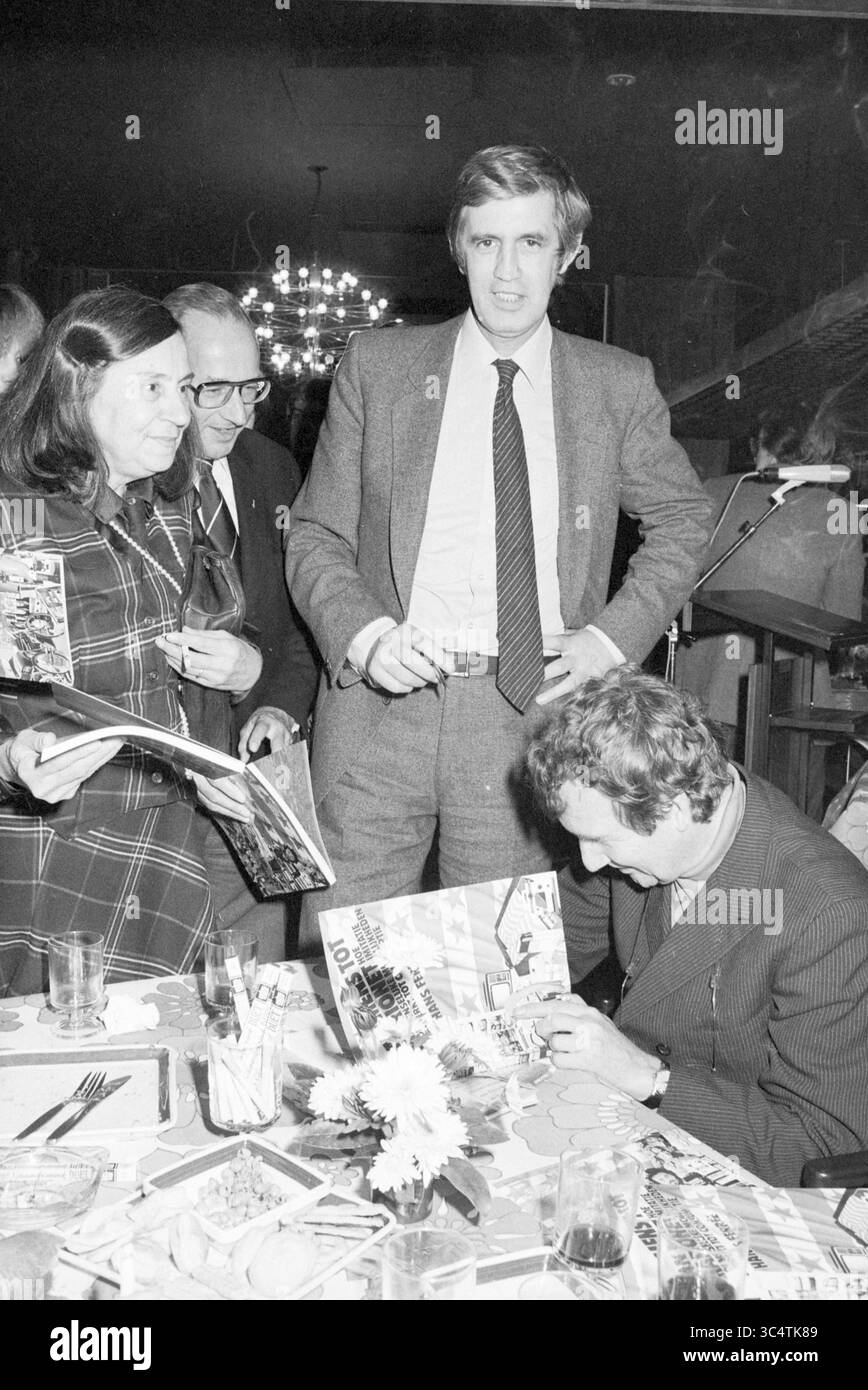 Spectrum Hans Ferre, Spectrum, 07-11-1978 Whizgle News, Dutch Desk, Niederlande, 1950-2000 Eine Gruppe von vier Personen versammelte sich an einem Tisch, führte Gespräche und sah sich Zeitschriften an. Ein Mann steht in einem Anzug mit einer selbstbewussten Haltung, während ein anderer sitzt und sich darauf konzentriert, einen Gegenstand zu signieren. Zwei Frauen in der Nähe beobachten die Interaktion, eine hält eine Zeitschrift. Die Atmosphäre lässt ein geselliges oder feierliches Ereignis vermuten. Stockfoto