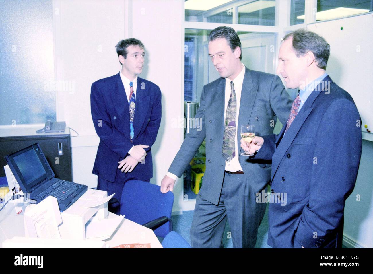 Rezeption Serac Haarlem, Haarlem, Niederlande, 17-11-1994 Whizgle News, Dutch Desk, Niederlande, 1950-2000 drei Fachleute diskutierten in einer Büroumgebung, wobei einer auf einen Computerbildschirm zeigte, während der andere ein Glas in formeller Kleidung hält. Stockfoto