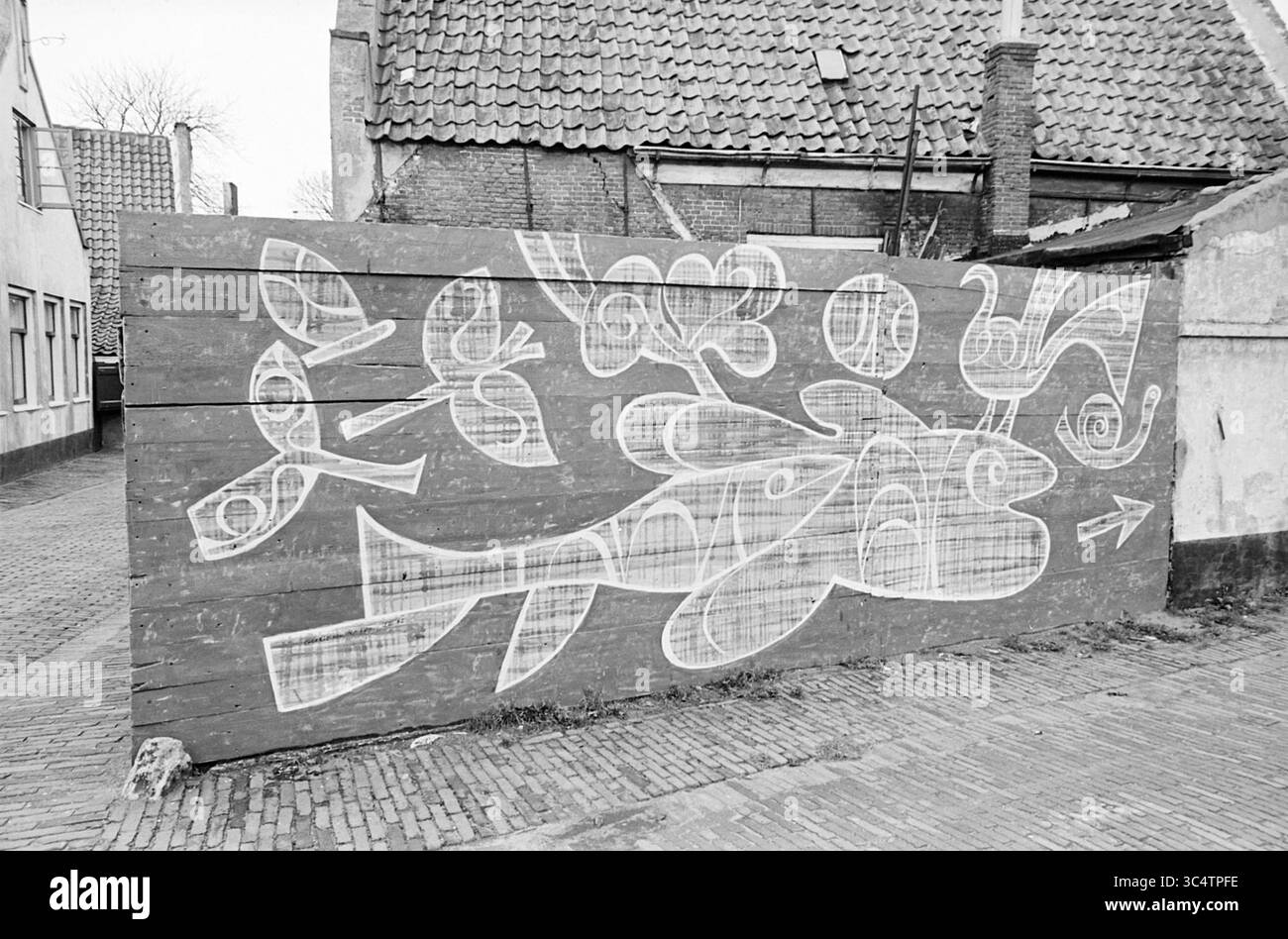 Porträt eines Gemüsehändlers (außen) mit gemaltem Zaun, 00-12-1964 Whizgle News, Dutch Desk, Niederlande, 1950-2000 Ein großes Wandbild zeigt abstrakte Formen und Formen, darunter einen Fisch, Blumen und skurrile Designs, gemalt auf einem Holzzaun in einer urbanen Umgebung. Das Kunstwerk verleiht der umgebenden Architektur einen kreativen Touch. Stockfoto