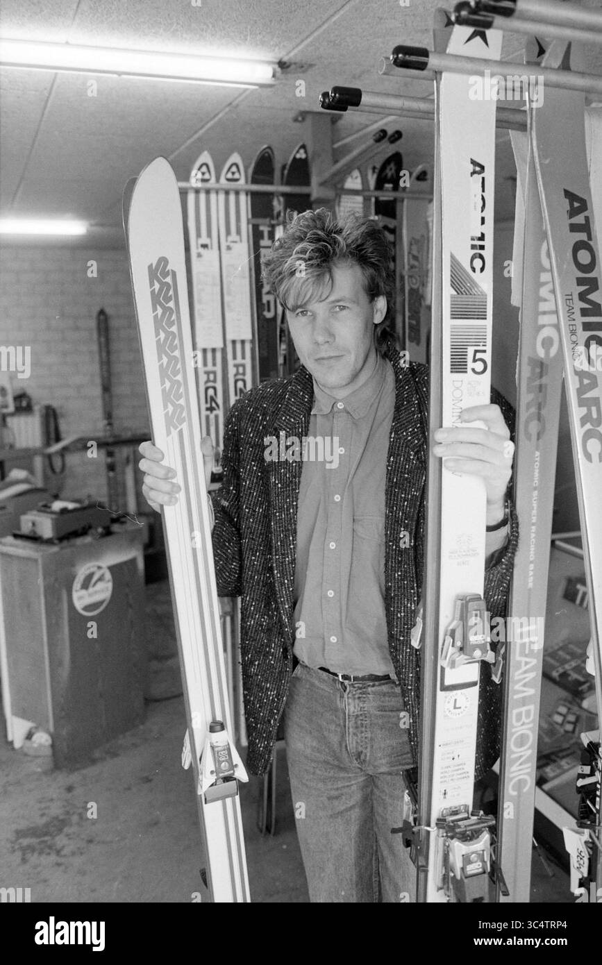 Timmers Ski Service Nieuw Vennep, Skisport, Nieuw-Vennep, 22-10-1987 Whizgle News, Dutch Desk, Niederlande, 1950-2000 Eine Person steht in einem Skigeschäft und hält zwei Paar Ski. Sie tragen ein stilvolles Outfit mit einer gemusterten Jacke und Jeans und blicken selbstbewusst in die Kamera, inmitten von Skiausrüstung. Der Hintergrund zeigt verschiedene Skiausrüstung, die die lebendige Kultur des Sports unterstreicht. Stockfoto
