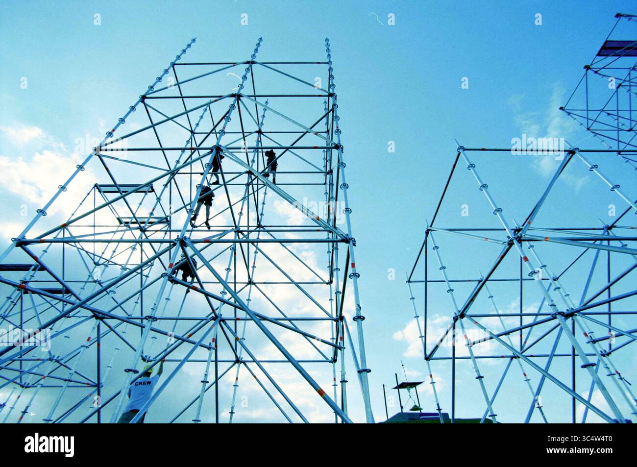 Mysteryland, Vijfhuizen, Vijfhuizen, 14-08-2003 Whizgle News, Dutch Desk, in den Niederlanden sieht man 1950-2000 Arbeiter, die Metallgerüste vor hellem Himmel aufsteigen, was die Komplexität der Installation verdeutlicht. Stockfoto
