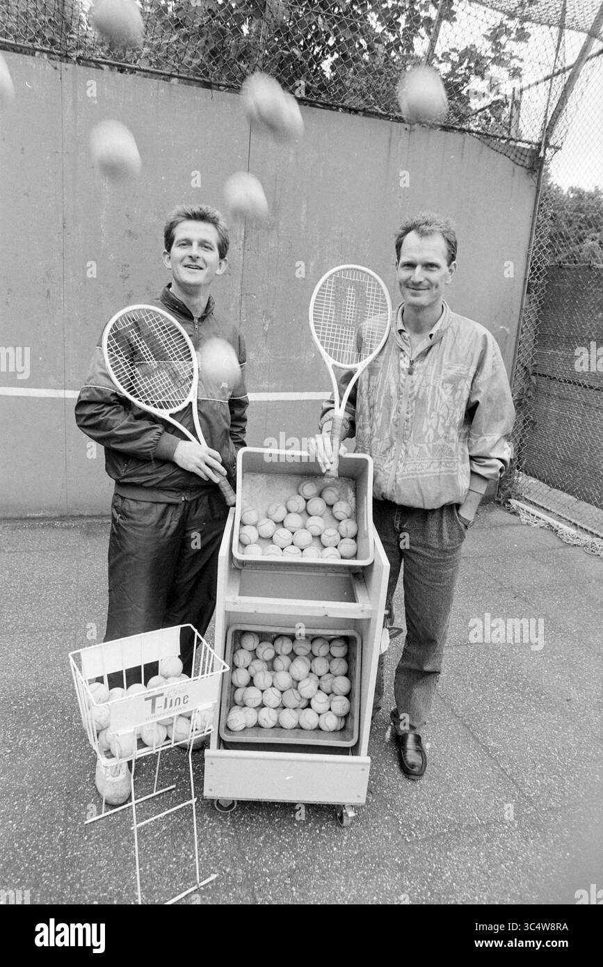 Mr. Zuidam + Bouten Tennisschule Groenendaal, Tennis, 02-08-1989 Whizgle News, Dutch Desk, Niederlande, 1950-2000 zwei Männer stehen auf einem Tennisplatz, jeder hält einen Schläger und lächelt. Hinter ihnen befindet sich ein Wagen mit Tennisbälle und ein kleiner Korb daneben. Die Szene vermittelt ein Gefühl der Begeisterung und des Vergnügens für den Sport. Stockfoto