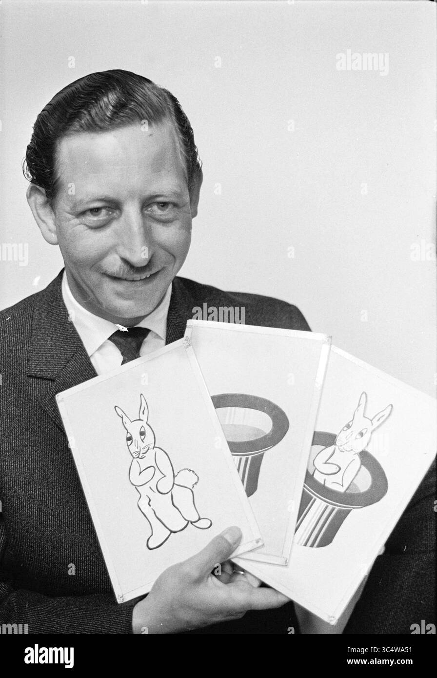Porträt Magician (man) Whizgle News, Dutch Desk, Niederlande, 1950-2000 Ein Mann in einem Anzug lächelt, während er drei illustrierte Karten mit einem Karikaturkaninchen hält, das aus dem Hut eines Magiers auftaucht. Stockfoto