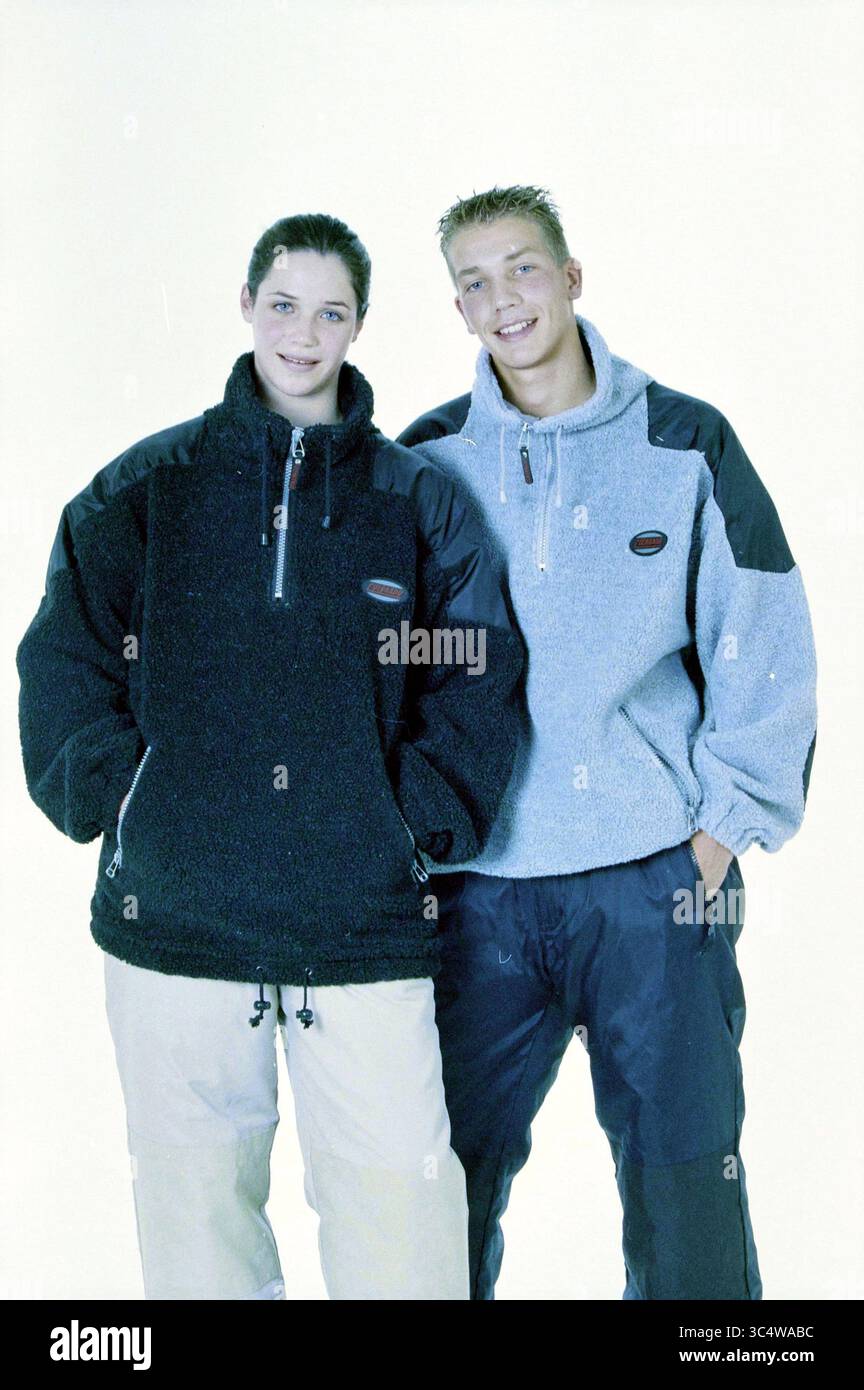 Snowboardanzüge, Aldi, 24-09-2000 Whizgle News, Dutch Desk, Niederlande, 1950-2000 Eine junge Frau und ein Mann stehen selbstbewusst nebeneinander, beide in gemütlichen, stylischen Fleecejacken mit Reißverschluss. Die Frau trägt eine schwarze Jacke, während der Mann eine hellgraue Version trägt. Sie kombinieren ihre Jacken mit einer lässigen Hose, die einen lässigen, aber modischen Outdoor-Look bietet. Stockfoto