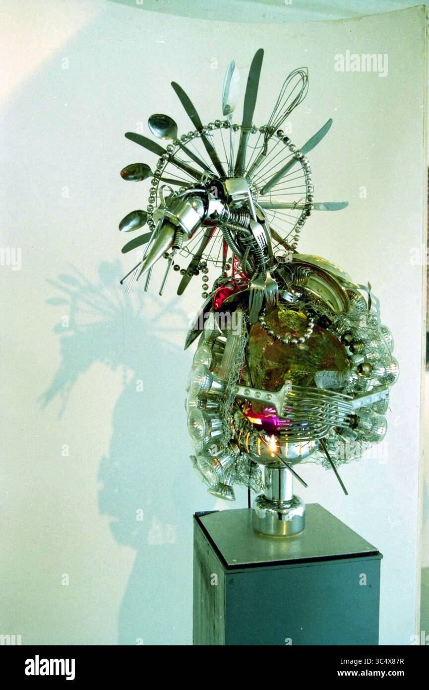Ostershow FF, Objekt (Vogel) im Ausstellungsraum, Haarlem, Niederlande, 10-04-2001 Whizgle News, Dutch Desk, Niederlande, 1950-2000 Eine skurrile Skulptur, die aus einer eklektischen Mischung von Utensilien und Glaswaren entstand und kreativ zu einem komplizierten, abstrakten Design zusammengesetzt wurde. Das Stück verfügt über eine dynamische Anordnung von Gabeln, Löffeln und verschiedenen Geschirren, die in einer optisch eindrucksvollen Darstellung gipfeln, die faszinierende Schatten wirft. Stockfoto