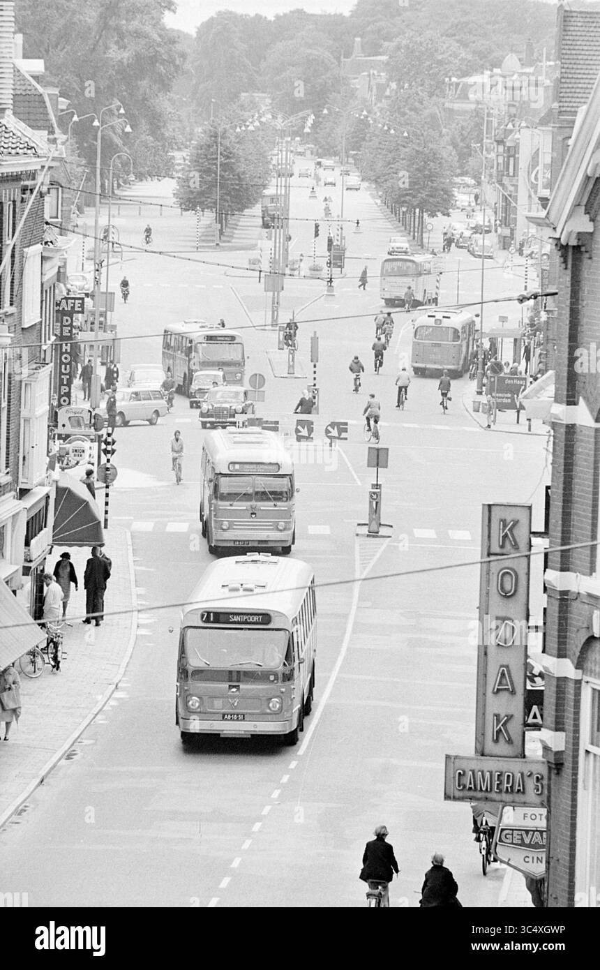 Geschäftig im Stadtzentrum von Haarlem., geschäftig, 21.06.1966 Whizgle News, Dutch Desk, Niederlande, 1950-2000 Eine geschäftige Straßenszene mit verschiedenen Fahrzeugen, darunter Busse und Fahrräder, die an einer geschäftigen Kreuzung vorbeifahren. Die Menschen schlendern entlang der Bürgersteige, mit Geschäften, die die Straßen im Schatten der Bäume säumen und eine lebhafte urbane Atmosphäre schaffen. Stockfoto