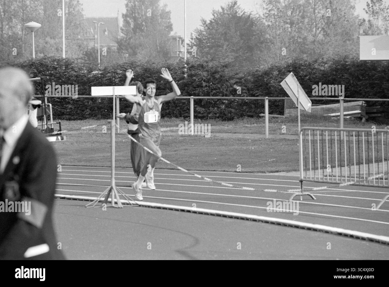 NK athletics 25 km Lisse, 12-10-1990 Whizgle News, Dutch Desk, Niederlande, 1950-2000 Ein Läufer überquert triumphierend die Ziellinie und hebt beide Hände zur Feier. Im Hintergrund beobachten Zuschauer und Beamte die Veranstaltung, während eine klare Spur den Kurs abgrenzt. Stockfoto