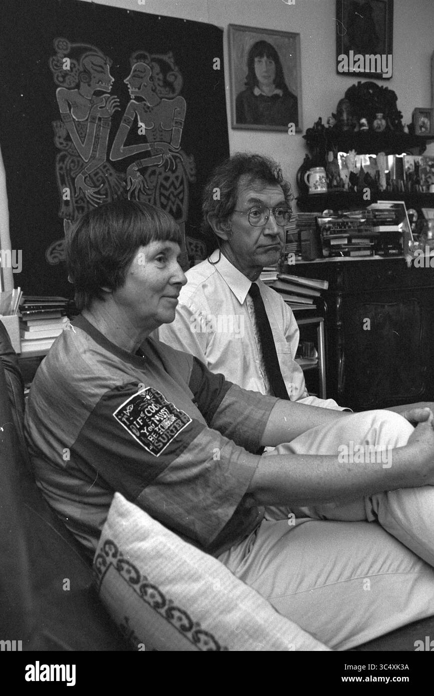 Bootsfahrt nach Indien, 03-07-1995 Whizgle News, Dutch Desk, Niederlande, 1950-2000 Eine Frau mit kurzen Haaren, die ein lässiges, farbenfrohes Oberteil trägt, sitzt aufmerksam neben einem Mann in Anzug und Krawatte, der nachdenklich erscheint. Hinter ihnen befindet sich eine Wand mit aufwändigen Kunstwerken, und die Regale sind mit Büchern und dekorativen Gegenständen gefüllt, was eine gemütliche, aber intellektuell anregende Atmosphäre schafft. Stockfoto