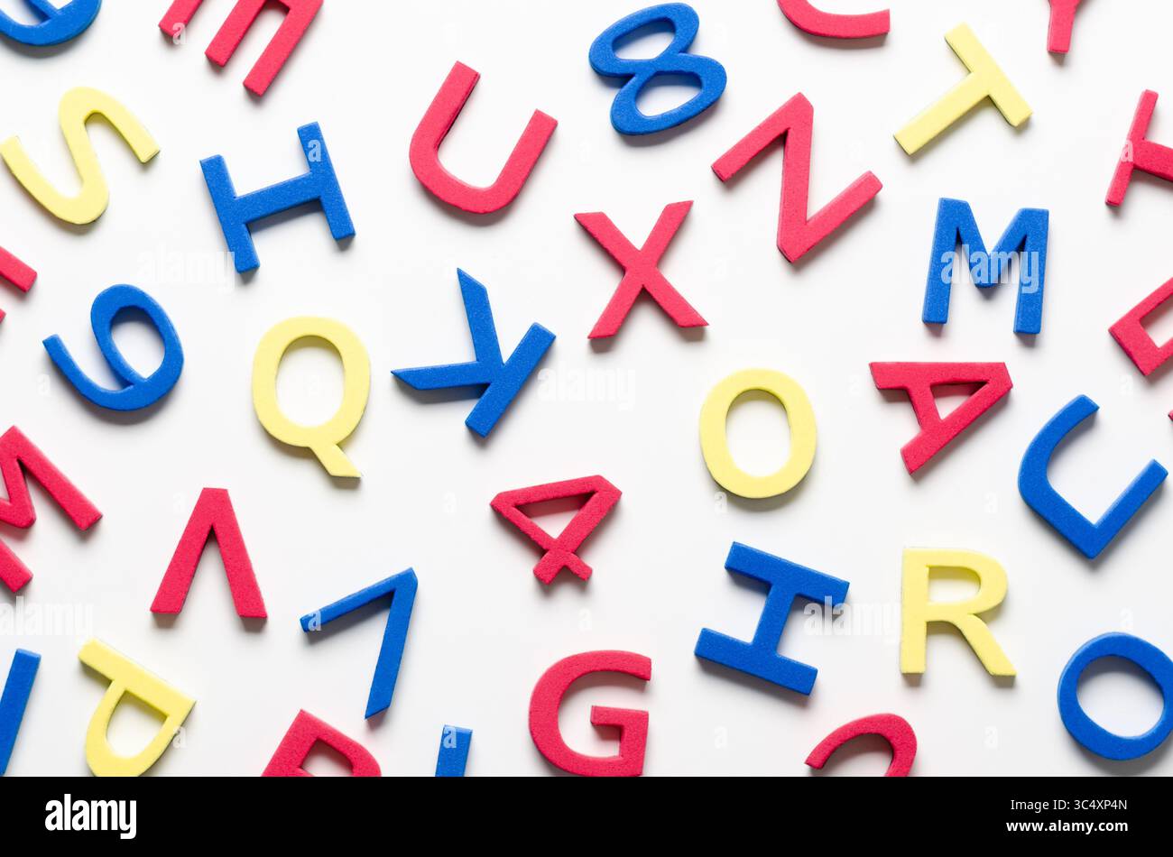 Bunte Buchstaben und Zahlen aus Schaumstoff auf weißem Hintergrund. Stockfoto
