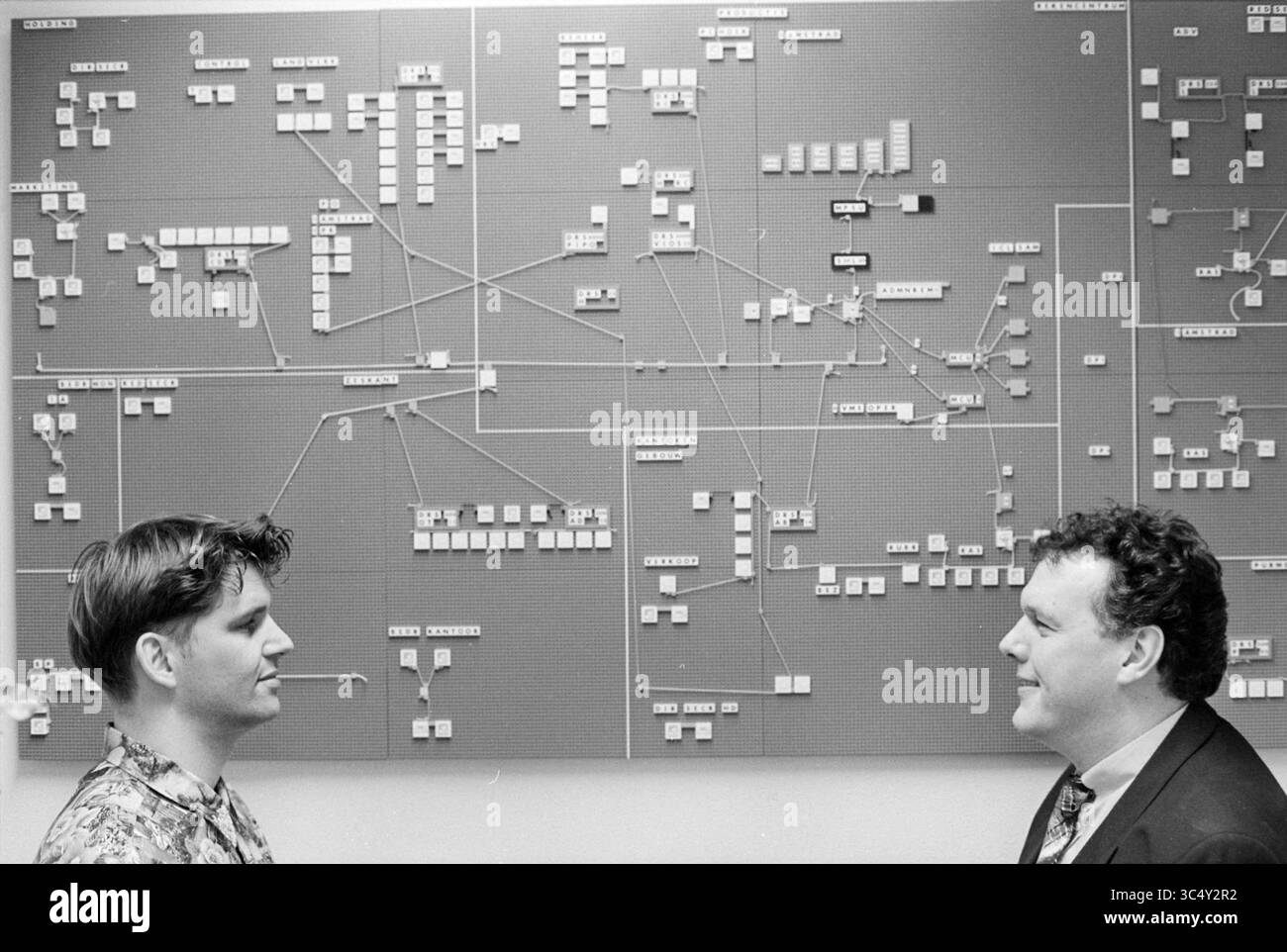 Computerorganisation Haarlems Dagblad, 21.01.1993 Whizgle News, Dutch Desk, Niederlande, 1950-2000 zwei Personen führen eine Diskussion vor einem großen, komplizierten Flussdiagramm oder Diagramm. Das Diagramm, gefüllt mit verbundenen Knoten und beschrifteten Feldern, stellt wahrscheinlich ein komplexes System oder Prozess dar. Jede Person scheint sich auf das Diagramm konzentriert zu zeigen, was eine gemeinsame Bemühung andeutet, die dargestellten Informationen zu verstehen oder zu erklären. Stockfoto