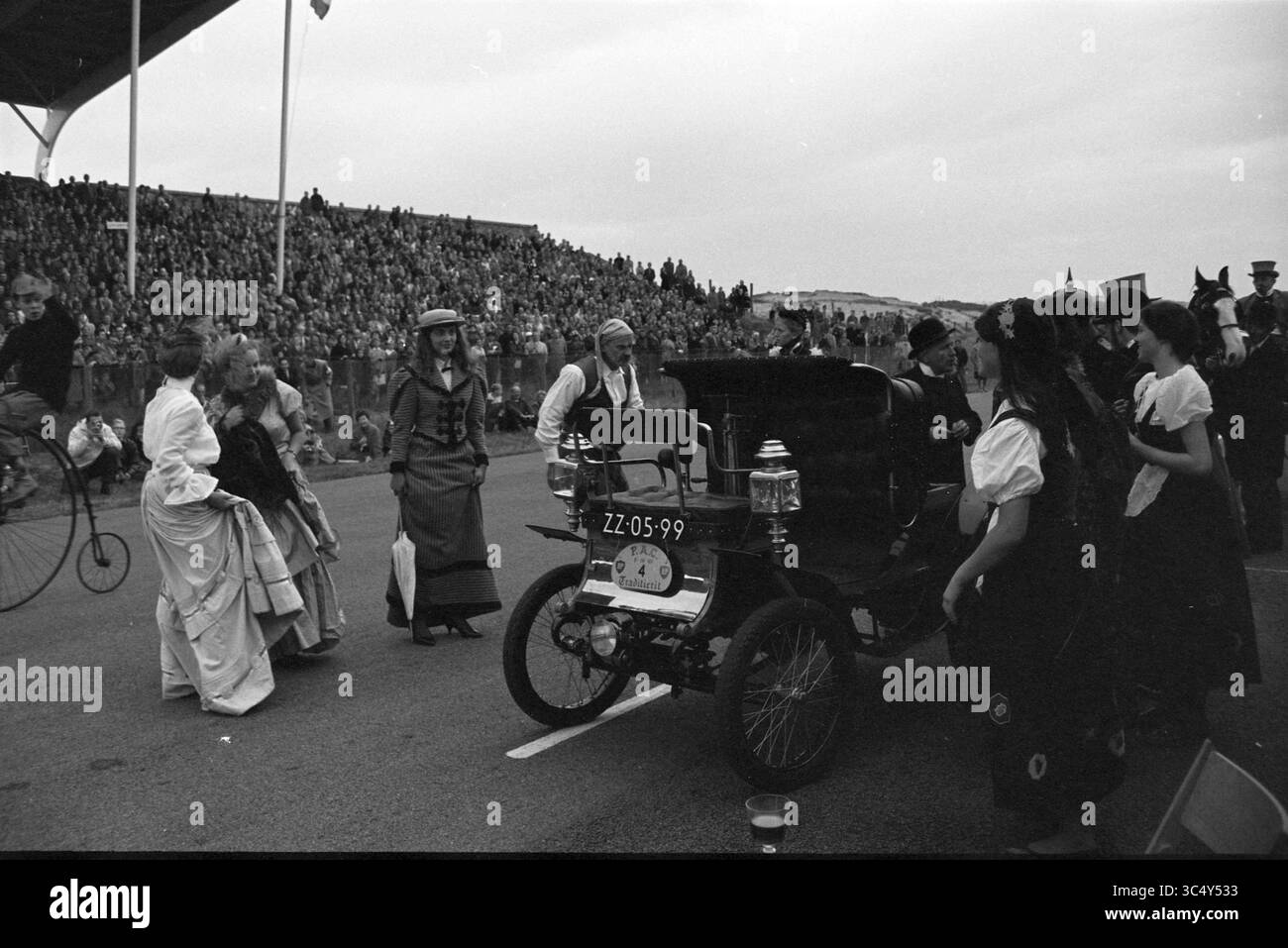 Jährliche traditionelle Fahrt des Pionier Automobielen Club (PAC) von Utrecht nach Zandvoort mit Tests auf der Zandvoort Strecke. 123 antike Autos aus sechs Ländern sind dabei., Zandvoort, 09-10-1960 Whizgle News, Dutch Desk, Niederlande, 1950-2000 In Einer lebendigen Szene bei einer historischen Veranstaltung versammeln sich Menschen in Vintage-Kleidung um einen Oldtimer, während die Zuschauer von der Seitenlinie aus zusehen. Die Atmosphäre ist festlich, mit einer Mischung aus Nostalgie und Feierlichkeiten, während die Teilnehmer an animierten Interaktionen teilnehmen. Stockfoto