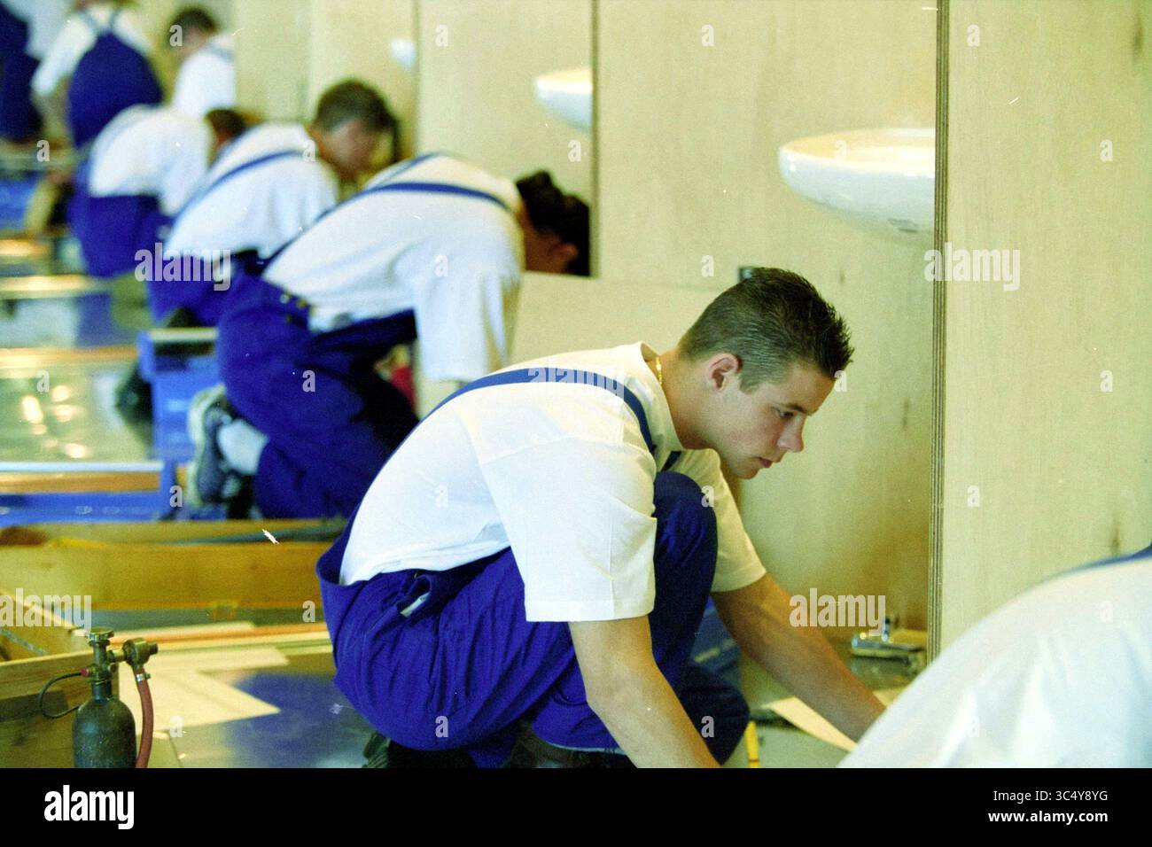 BEST man Award IJmuiden, IJmuiden, Niederlande, 09-04-2002 Whizgle News, Dutch Desk, Niederlande, 1950-2000 Eine Gruppe qualifizierter Auszubildender konzentriert sich intensiv auf Sanitäranlagen und arbeitet fleißig an einzelnen Stationen, die mit Waschbecken und Werkzeugen ausgestattet sind. Jeder Teilnehmer trägt koordinierte blaue Overalls und weiße Hemden, um eine gemeinsame Lernumgebung zu demonstrieren. Stockfoto