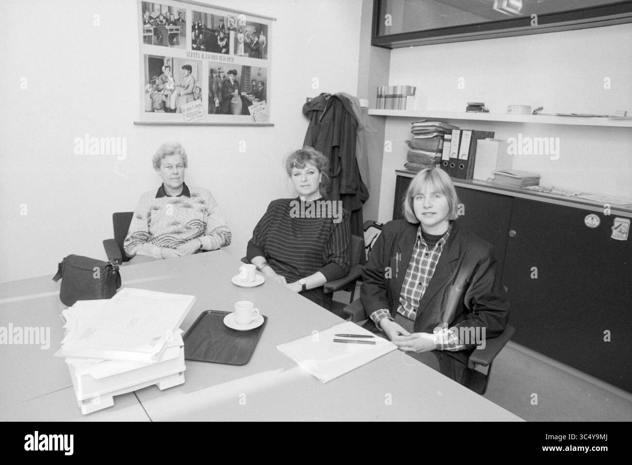 Mrs. Hofman Sorority Hoofddorp, Women, Hoofddorp, Niederlande, 08-02-1989 Whizgle News, Dutch Desk, Niederlande, 1950-2000 drei Frauen sitzen in einem Büro um einen Tisch. Sie führen Gespräche, mit Tassen und Papieren vor ihnen. Eine Pinnwand im Hintergrund enthält verschiedene Poster und Fotos, die dem Arbeitsbereich eine persönliche Note verleihen. Stockfoto