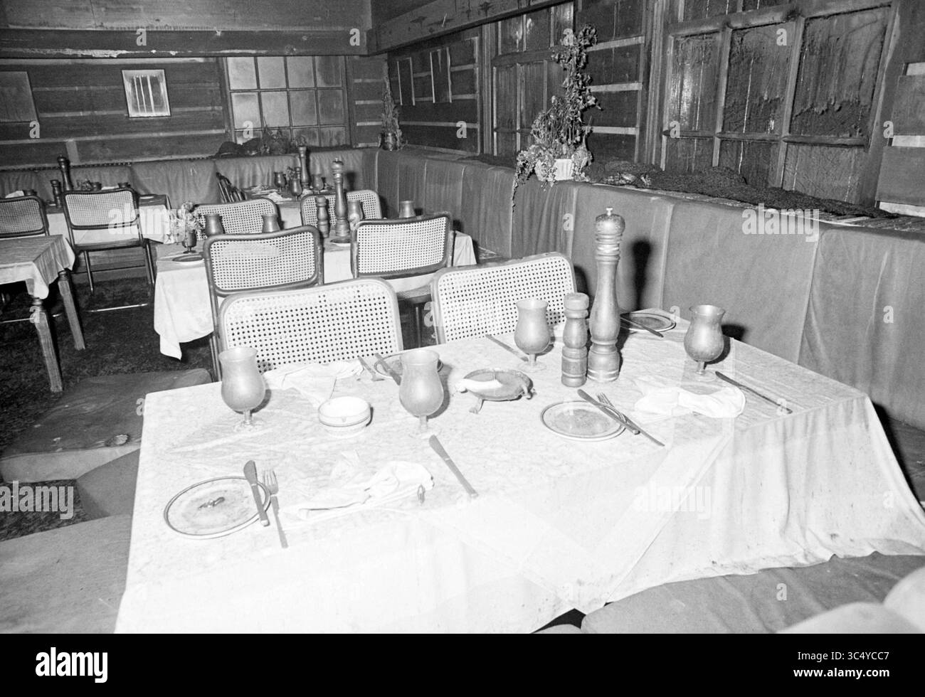 Feuer + Ruin Posthoeve (HFC Haarlem Standort), Feuer, Feuerwehr, 04.08-1980 Whizgle News, Dutch Desk, Niederlande, 1950-2000 ein intimes Ambiente mit Tischen, die mit weißen Tüchern überzogen sind und mit Tellern und Utensilien geschmückt sind. Glaswaren und eine Pfeffermühle sorgen für eine einladende Atmosphäre. Die rustikale Einrichtung wird durch Holzwände und kleine Fensteröffnungen ergänzt, die den Charme des Raumes unterstreichen. Stockfoto