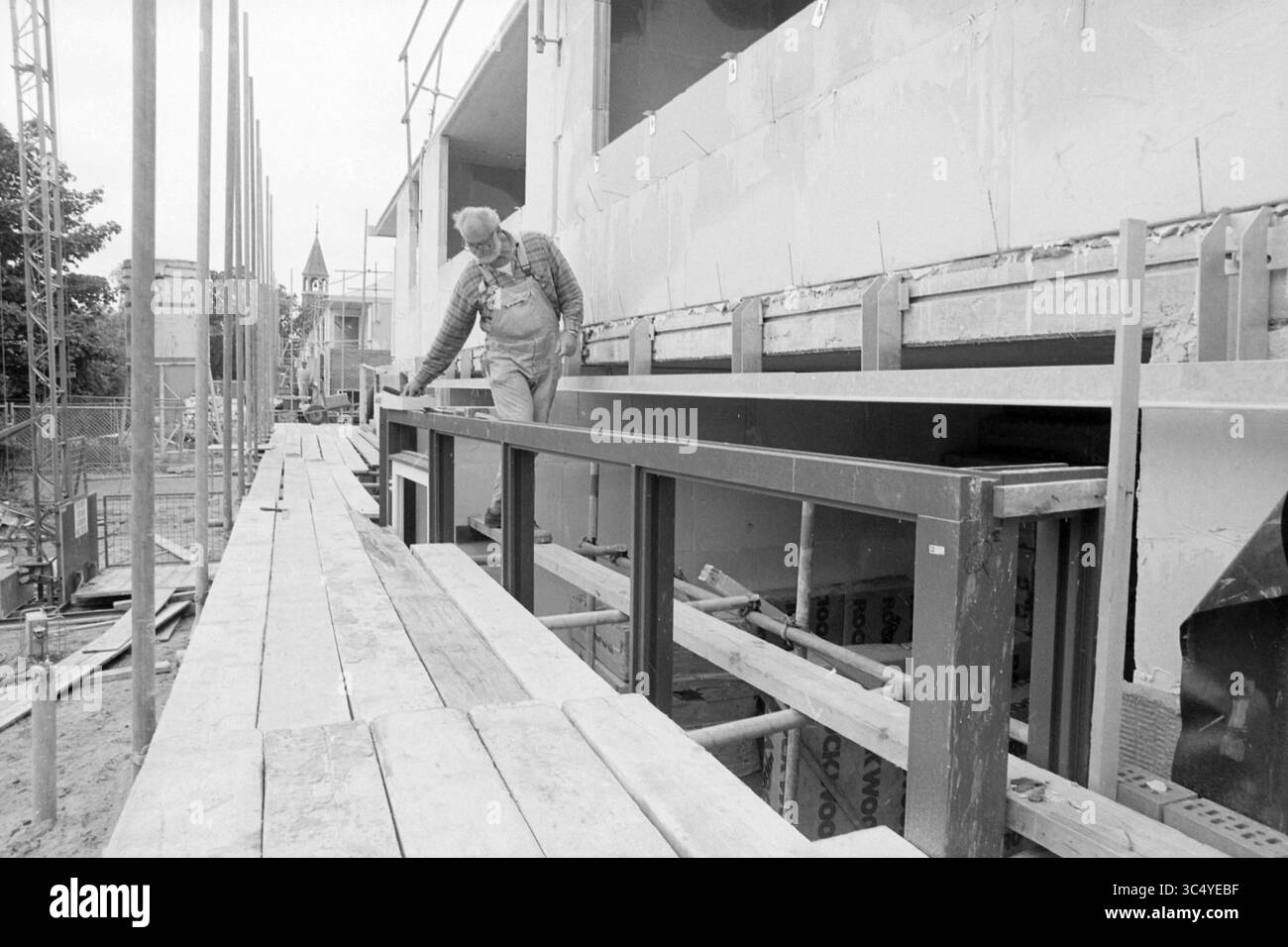 Neu gebaute Häuser, Ramplaan, Haarlem, Ramplaan, Niederlande, 24-05-1994 Whizgle News, Dutch Desk, Niederlande, 1950-2000 Ein Bauarbeiter navigiert sorgfältig eine Reihe von Holzbalken, um die Stabilität der provisorischen Bauwerke zu gewährleisten, während der Baufortschritt hinter ihm fortfährt. Gerüste bilden die Szene und heben eine aktive Baustelle hervor. Stockfoto