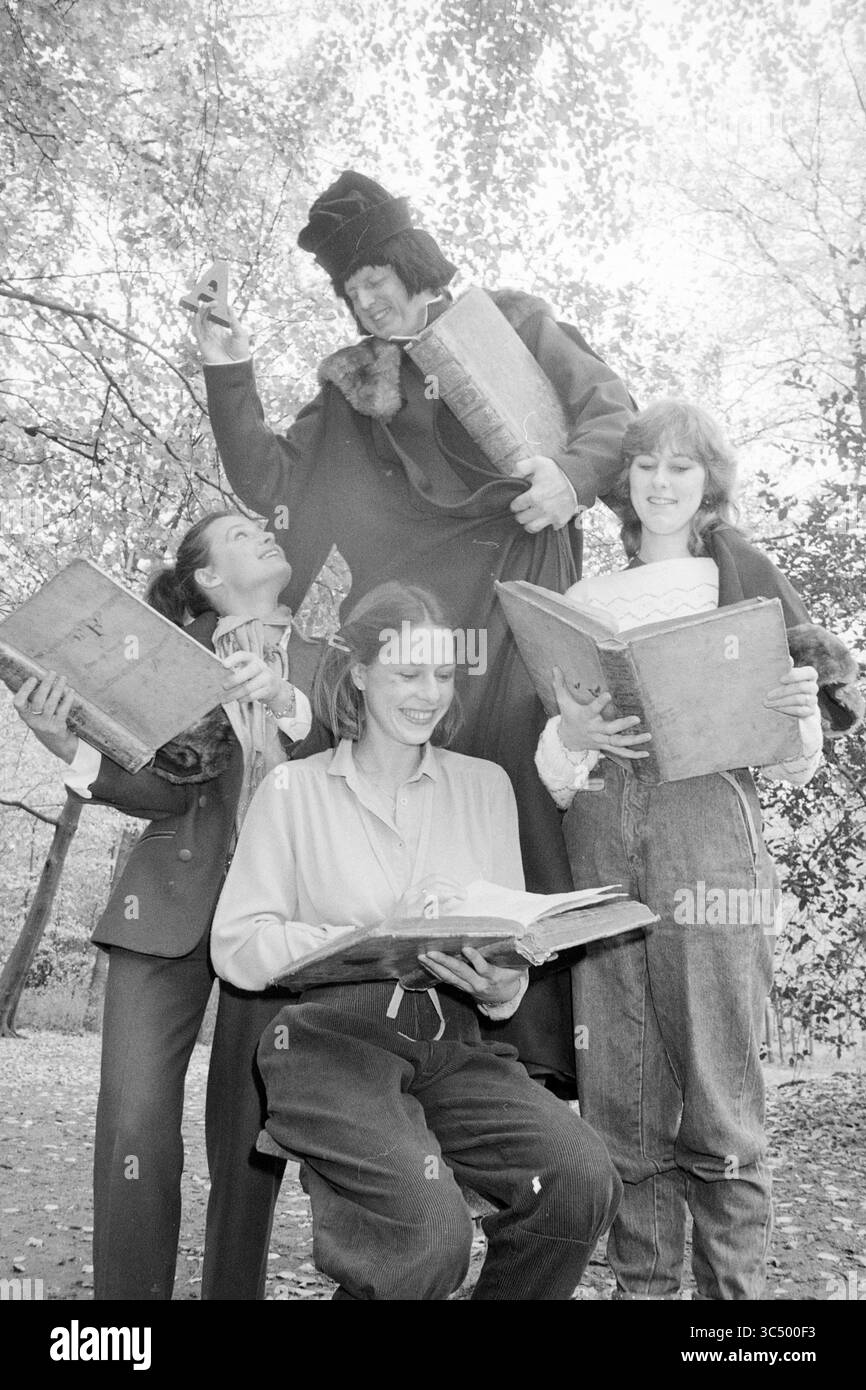 L.J. Coster mit Mädchen, Erfinder der Druckerei, Bücher und Buchhändler, 10-11-1982 Whizgle News, Dutch Desk, Niederlande, 1950-2000 Eine vierköpfige Gruppe hält in einem verspielten Ambiente im Freien Bücher, während sie miteinander interagiert, wobei eine Person humorvoll über die anderen steigt. Ihre Ausdrücke vermitteln Freude und Kameradschaft, was ein unbeschwertes literarisches Thema andeutet. Stockfoto