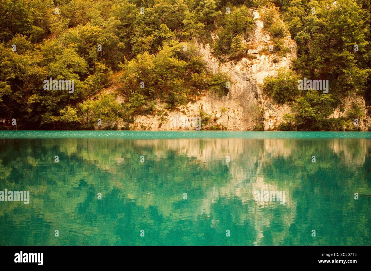 Ruhiger See mit Waldspiegelung und warmer Vintage-Atmosphäre. Perfekt für Ökotourismus und Wellness-Konzepte Stockfoto
