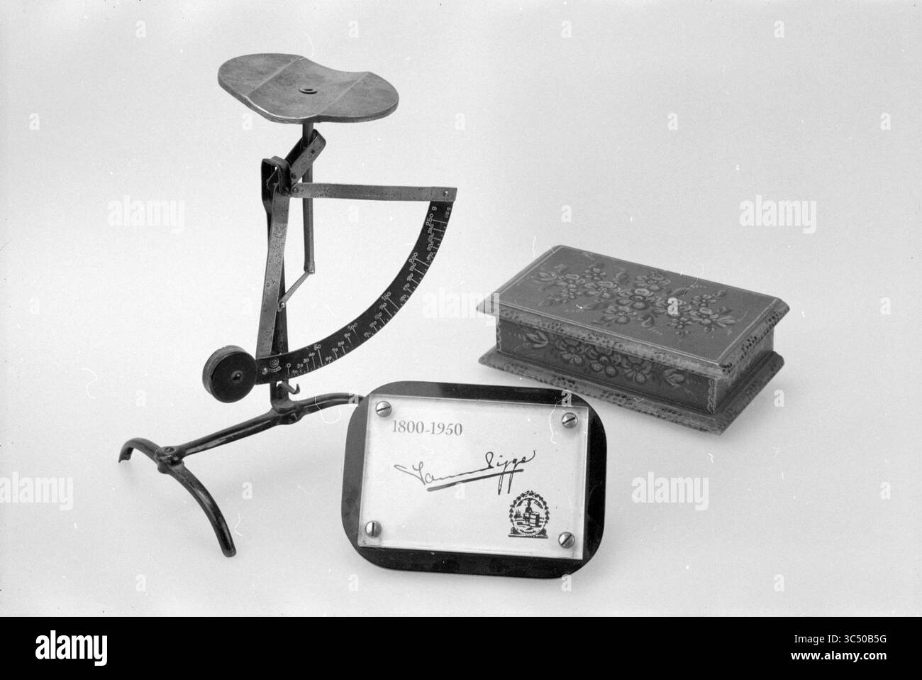 Verschiedene Artikel J. v.d. Pigge 200 Jahre, Haarlem, Niederlande, 23-02-2000 Whizgle News, Dutch Desk, Niederlande, 1950-2000 Eine Vintage-Waage, eine kunstvolle dekorative Box und eine Gedenktafel aus den Jahren 1800-1950, mit einer Signatur. Das Arrangement spiegelt eine Mischung aus handwerklichem Können und historischer Bedeutung wider. Stockfoto