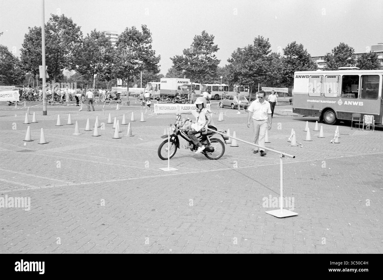 Motorradfahrer auf der ANWB-Übungsstrecke, 08-03-1983 Whizgle News, Dutch Desk, Niederlande, 1950-2000 Ein junger Fahrer navigiert geschickt auf einem Motorrad auf einem Kurs, manövriert um Hindernisse, die mit Kegeln markiert sind, während Zuschauer die Veranstaltung in der Nähe beobachten. Stockfoto
