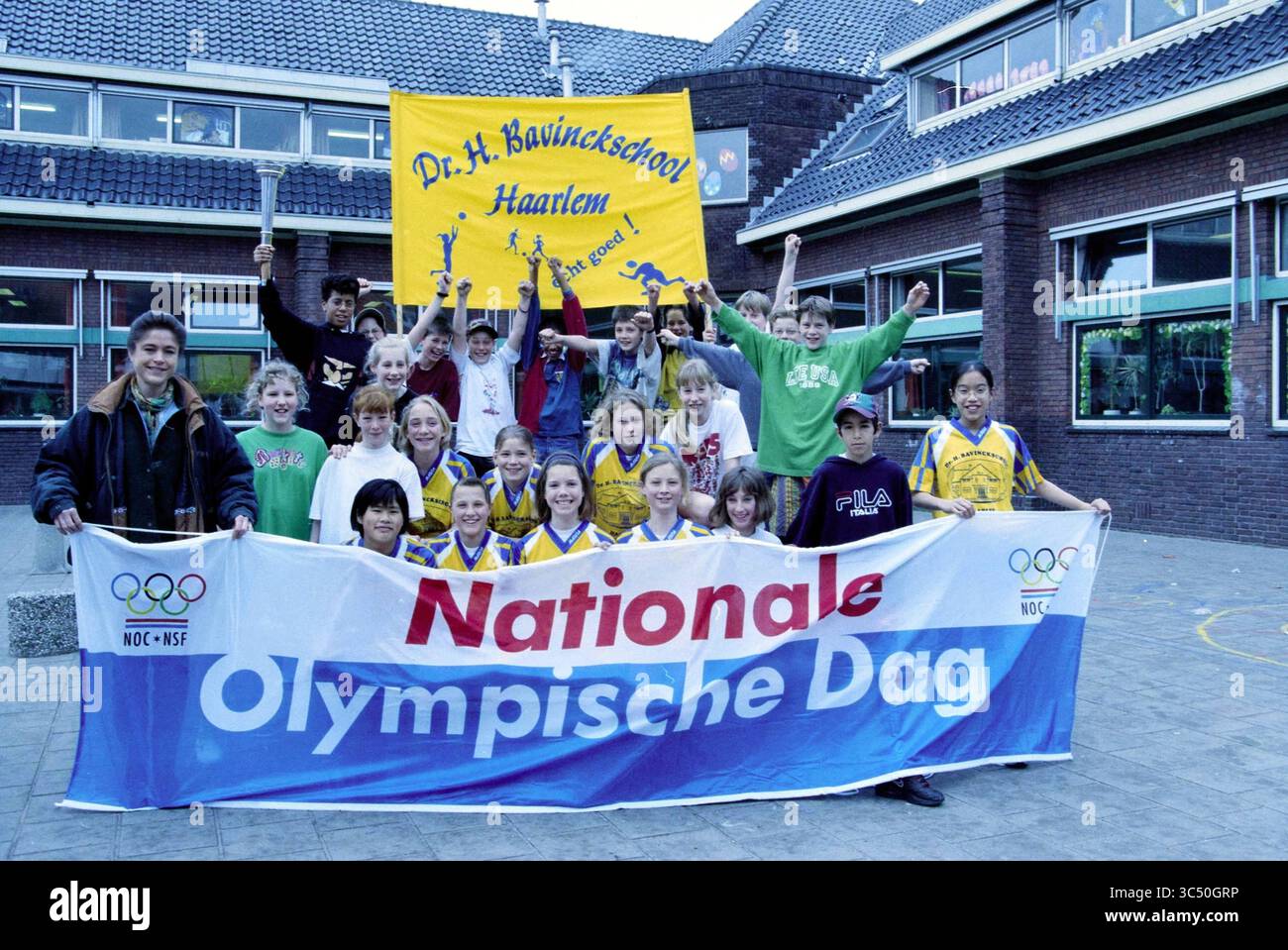 Olympiasieger Yvonne van Gennip (vorne links) im Rahmen des Nationalen Olympischen Tages NOC*NSF in der Dr. H. Bavinckschool, Rechthuisstraat Ecke Ambachtstraat, Haarlem, Rechthuisstraat, Niederlande, 31 03.03.1998 Whizgle News, Dutch Desk, Niederlande, 1950-2000 Eine lebhafte Gruppe von Kindern und Jugendlichen versammelte sich vor einer Schule und zeigte stolz Banner, die den nationalen Olympischen Tag feiern, zusammen mit ihren Sportuniformen. Sie strahlen Begeisterung und Schulgeist aus, wenn sie für die Kamera posieren und ein Gefühl von Gemeinschaft und Teamarbeit vermitteln. Stockfoto