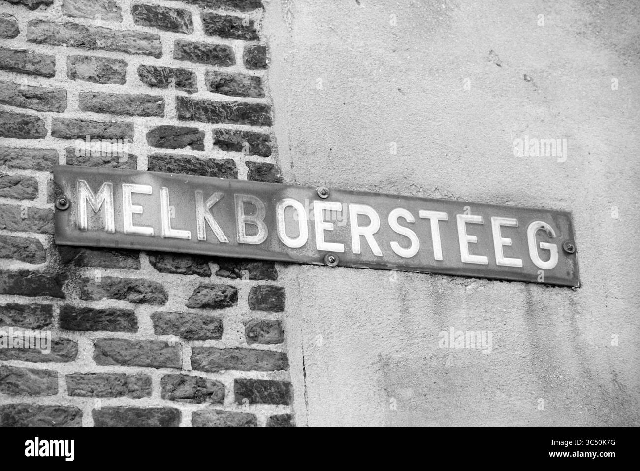 Verschiedene Straßenschilder, 10-05-1992 Whizgle News, Dutch Desk, Niederlande, 1950-2000 an einer strukturierten Wand ist Ein verwittertes Straßenschild mit der Aufschrift „MELKBOERSTEGE“ angebracht, das die Aufmerksamkeit auf den historischen Charakter des Ortes lenkt. Stockfoto
