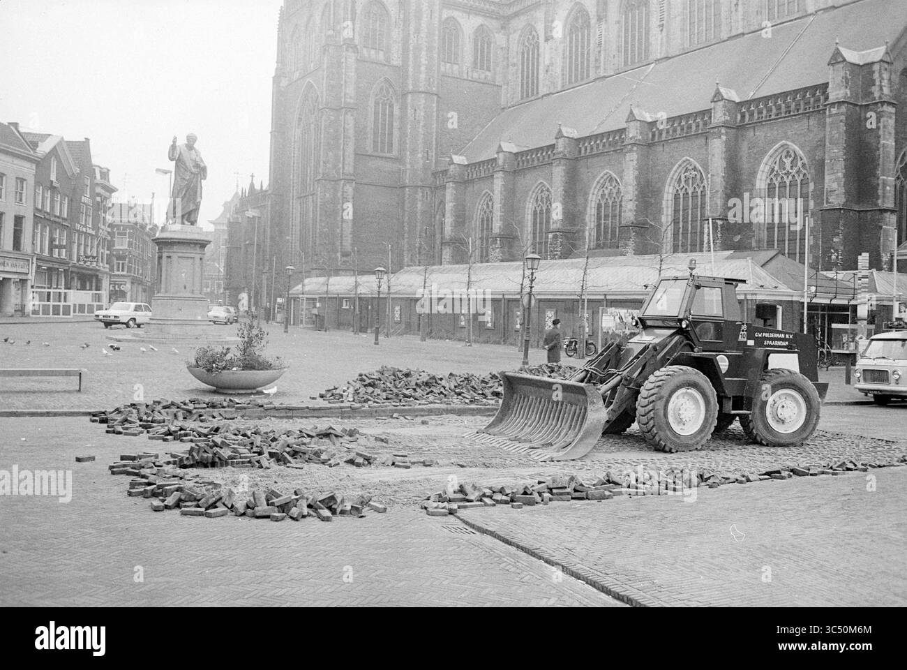 Aktivitäten Grote Markt, Aktivitäten, Haarlem, Grote Markt, Niederlande, 29-02-1972 Whizgle News, Dutch Desk, Niederlande, 1950-2000 Ein Baufahrzeug räumt Pflastersteine auf einem Stadtplatz ab, im Hintergrund stehen eine Statue und eine historische Kirche. In der Nähe säumen leere Läden die Straße und Tauben sind zu sehen. Stockfoto