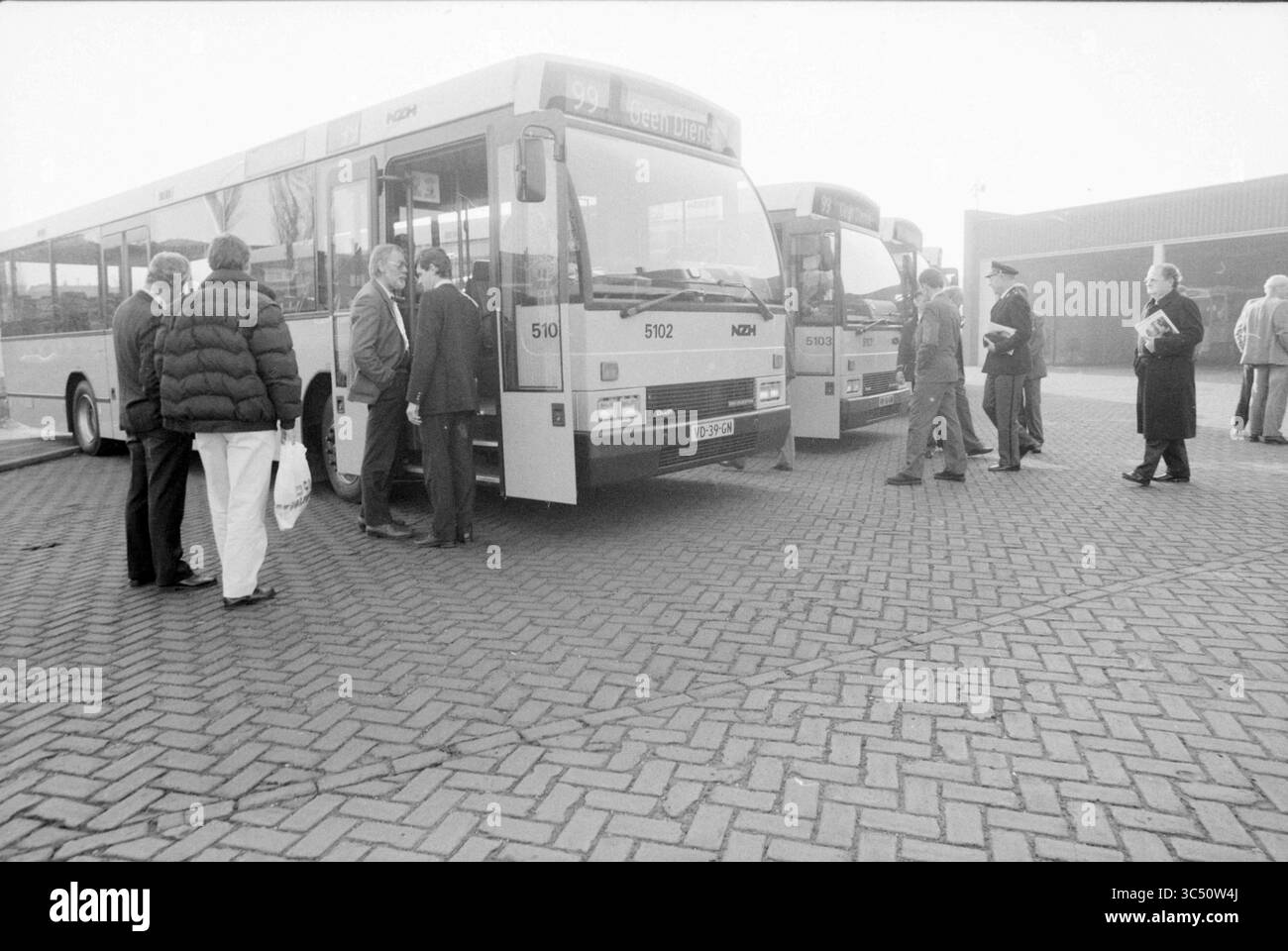 Vorstellung neuer Stadtbusse NZH, Noord Zuid Hollandse Vervoersmaatschappij N.V., NZ, 08-02-1989 Whizgle News, Dutch Desk, Niederlande, 1950-2000 Eine Gruppe von Menschen versammelt sich in der Nähe von zwei Bussen, die auf einem gemusterten Gehsteig abgestellt sind, um sich auf das Einsteigen vorzubereiten. Einige Personen tragen formelle Kleidung, andere tragen legere Kleidung, was eine lebhafte Szene der Vorfreude an einer Transitstation schafft. Stockfoto