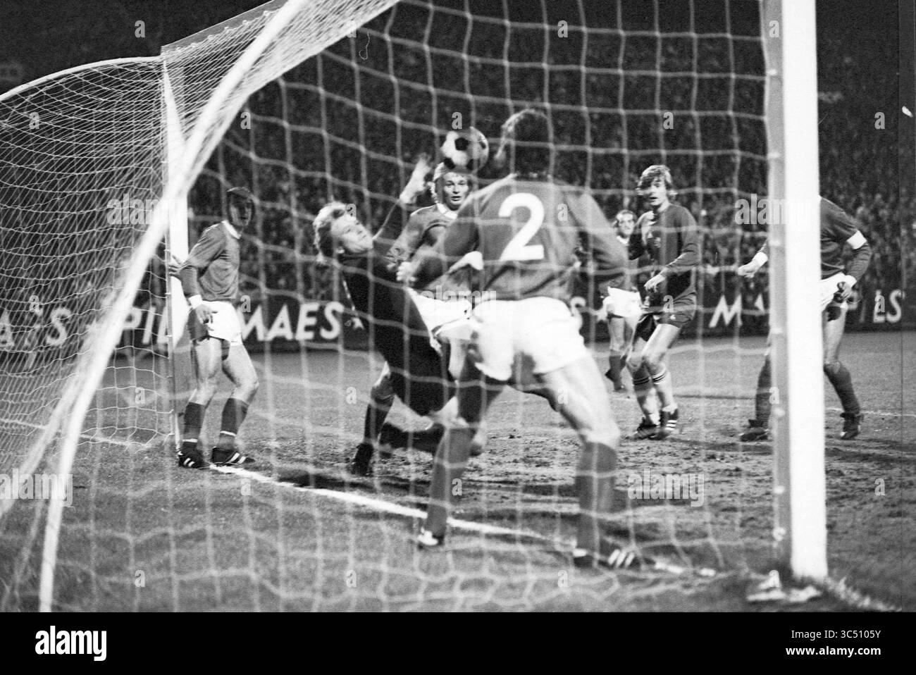 FC Antwerp - Ajax, Football, 13-11-1974 Whizgle News, Dutch Desk, Niederlande, 1950-2000 Ein angespannter Moment während eines Fußballspiels, in dem ein Torhüter sich greift, um einen entscheidenden Einschlag zu erzielen, während Spieler beider Teams das Ergebnis voraussehen. Das Netz ist sichtbar vom Aufprall verzerrt, was die Intensität des Spiels unterstreicht. Stockfoto