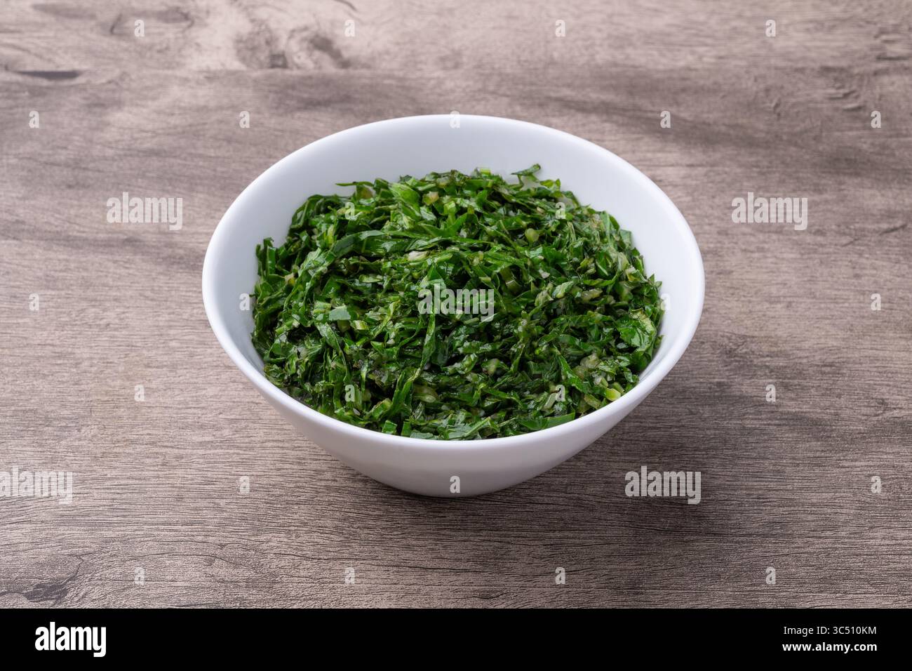 Gekochte Grünkohl-Streifen, typisch brasilianische Feijoada-Beilage in einer Schüssel über einem Holztisch. Stockfoto