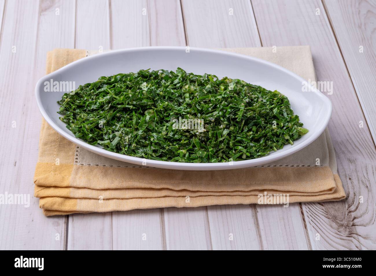 Gekochte Grünkohl-Streifen, typisch brasilianische Feijoada-Beilage in einer Schüssel über einem Holztisch. Stockfoto