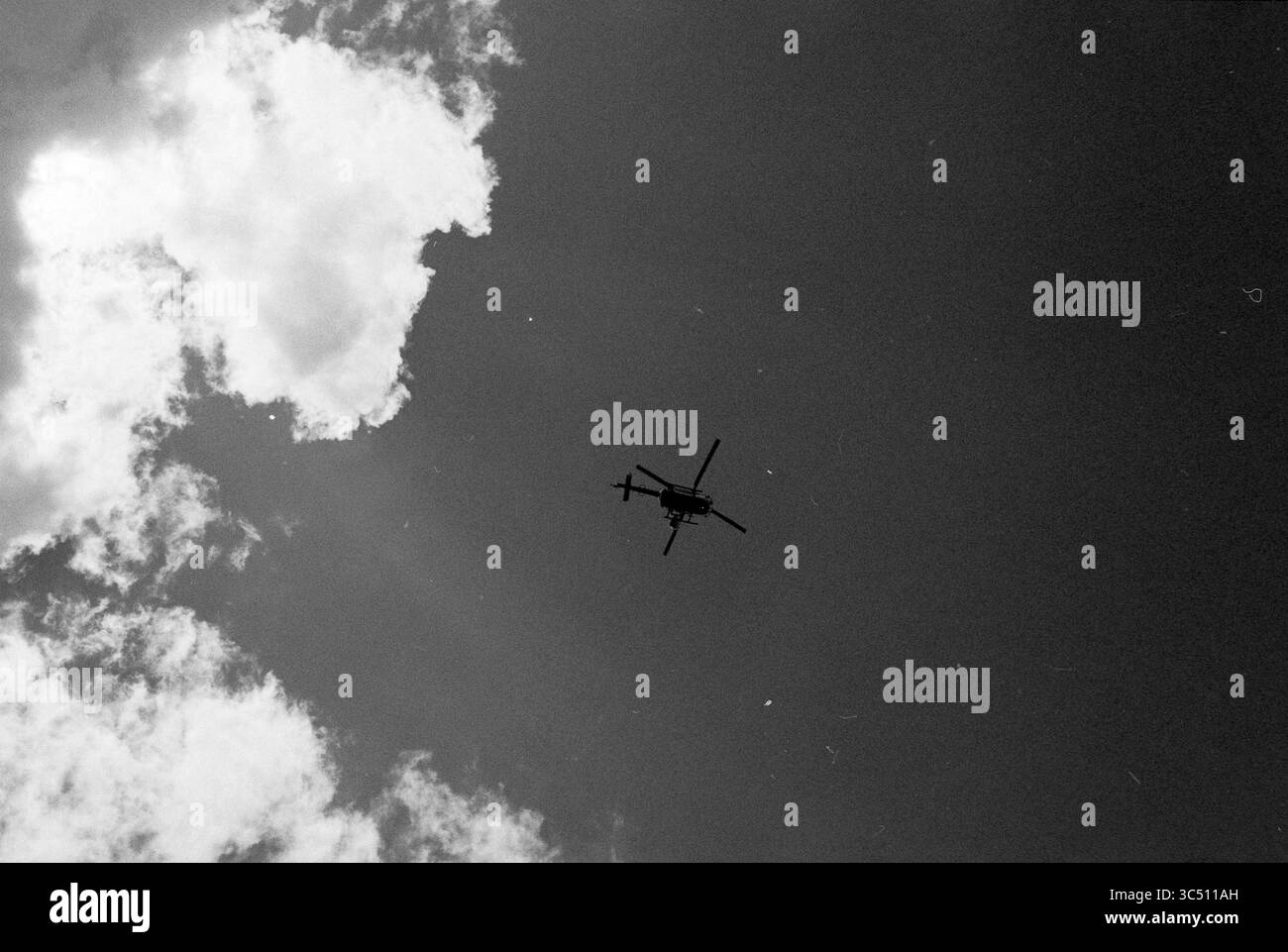Schiphol, Schiphol, 25-05-1990 Whizgle News, Dutch Desk, Niederlande, 1950-2000 Ein Hubschrauber schwingt unter Wolken und wirft eine Silhouette über den Himmel. Stockfoto