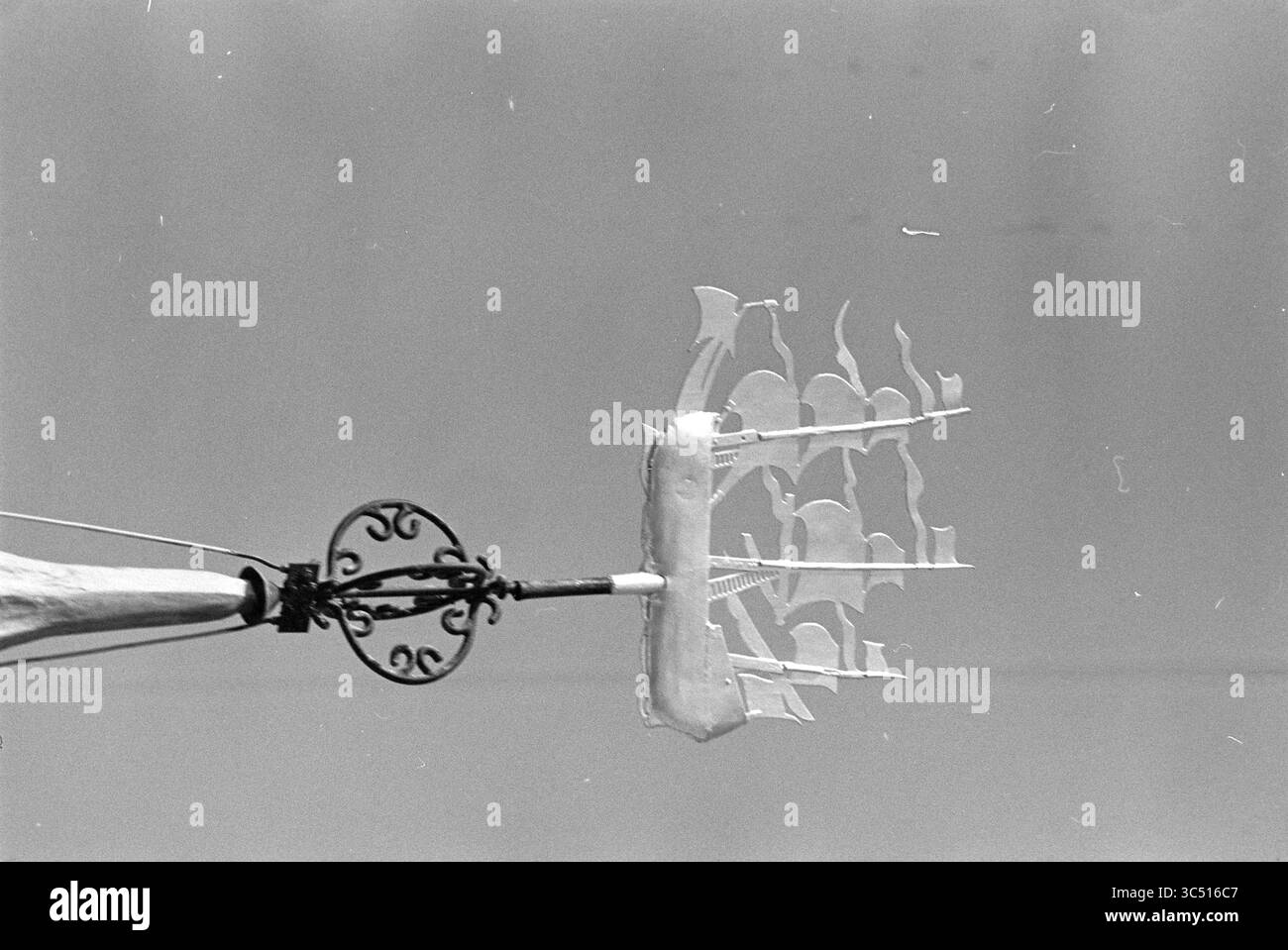 Windfahne auf dem Rathaus von Zandvoort, Gemeinderat von Zandvoort, Zandvoort, Zandvoort, 02-05-1980 Whizgle News, Dutch Desk, Niederlande, 1950-2000 Ein dekoratives Handgerät verfügt über eine filigrane Anordnung aus komplexen Formen, die Segeln oder architektonischen Formen ähneln und über einem kunstvollen Griff eine auffällige visuelle Komposition schaffen. Stockfoto