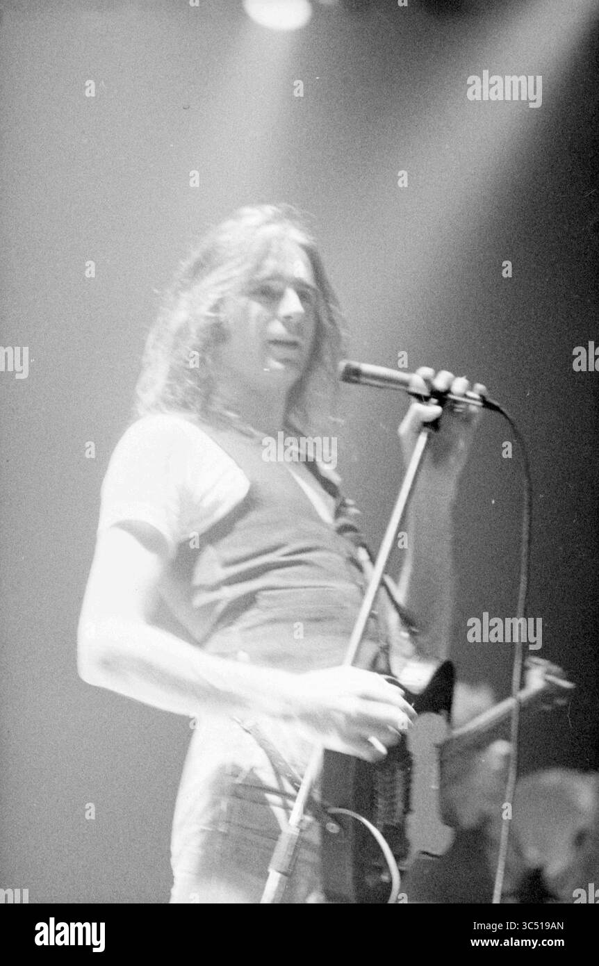 Concert Status Quo, Concerts, 25-02-1977 Whizgle News, Dutch Desk, Niederlande, 1950-2000 Ein Musiker, der leidenschaftlich auf der Bühne auftritt, ein Mikrofon in der einen Hand hält, während er mit der anderen eine Gitarre packt und Energie und Verbindung mit dem Publikum ausstrahlt. Stockfoto