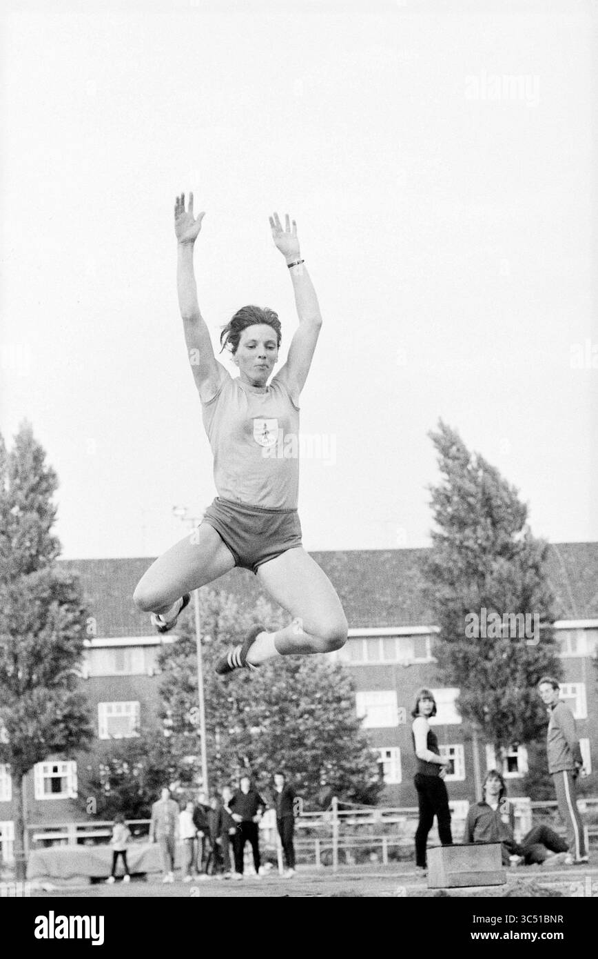 Athletics, Whizgle News, Dutch Desk, Niederlande, 1950-2000 ein Athlet in der Mitte eines Weitsprung-Wettkampfes, der Entschlossenheit und Leichtathletik zum Ausdruck bringt, während die Zuschauer im Hintergrund beobachten. Stockfoto