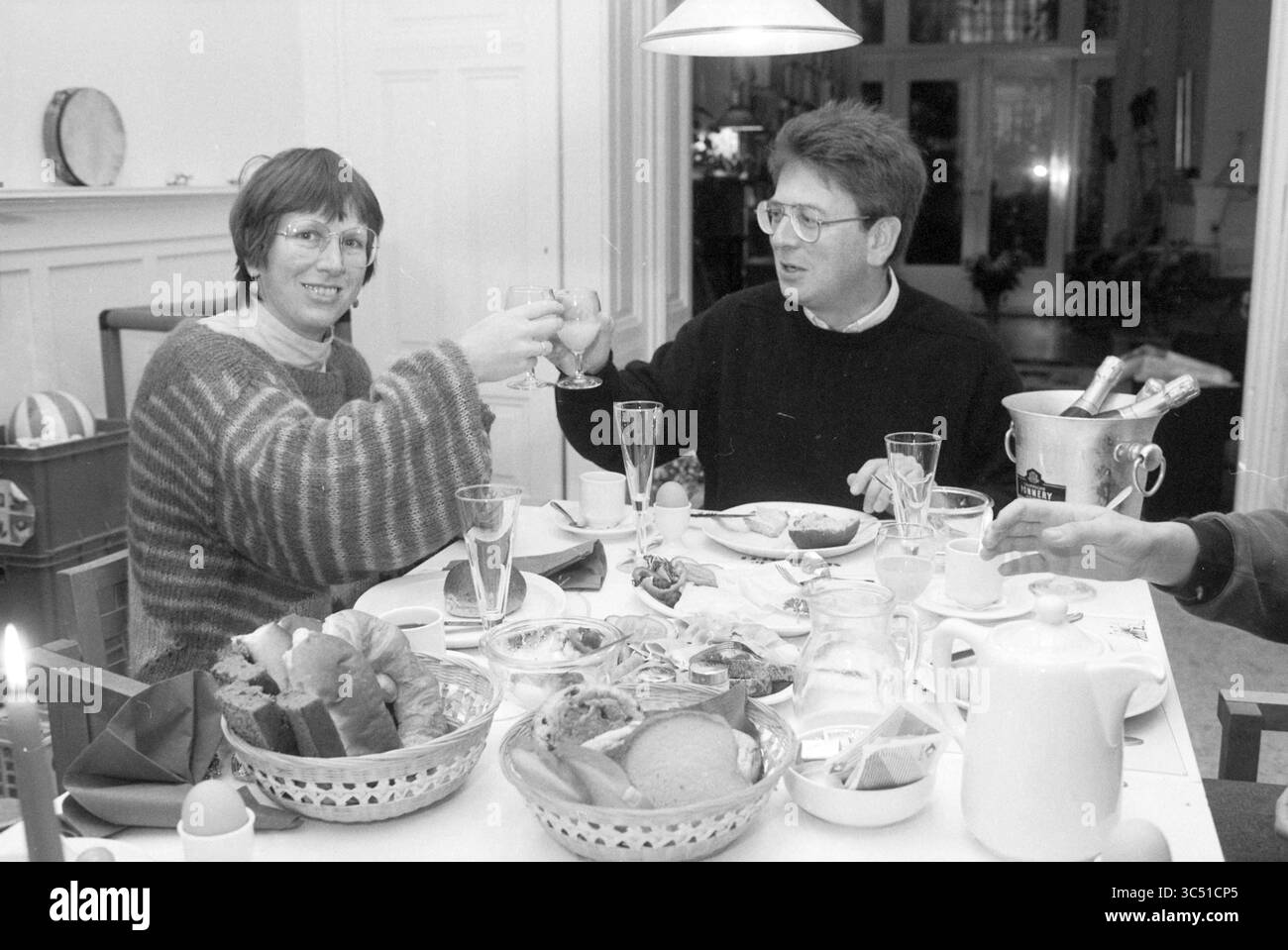 Champagnerfrühstück für Jacques Wallage, Staatssekretär der PvdA, 07-11-1989 Whizgle News, Dutch Desk, Niederlande, 1950-2000 Eine fröhliche Zusammenkunft an einem Esstisch, gefüllt mit einer Auswahl an Speisen und Getränken, während zwei Personen ihre Gläser in einem Toast heben, umgeben von Tellern und einer festlichen Atmosphäre. Stockfoto