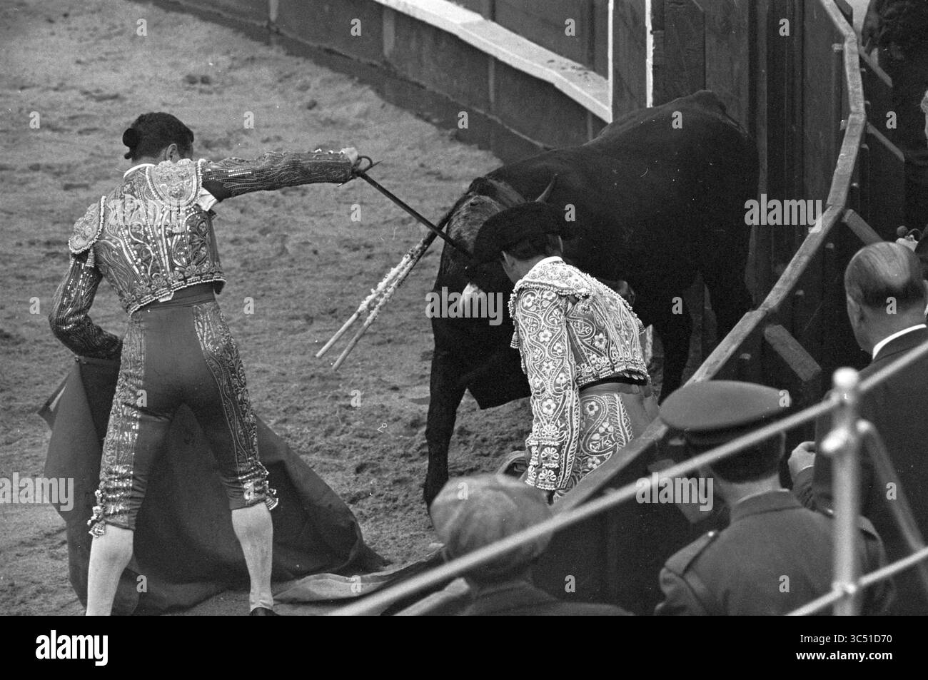 Bullfight Whizgle News, Dutch Desk, Niederlande, 1950-2000 zwei Matadoren nehmen an einem traditionellen Stierkampf-Spektakel Teil, einer schwingt ein cape und der andere bereitet sich darauf vor, bei der Aufführung zu helfen. Die Spannung des Augenblicks ist spürbar, umgeben von einem Publikum, das den Wettbewerb beobachtet. Stockfoto