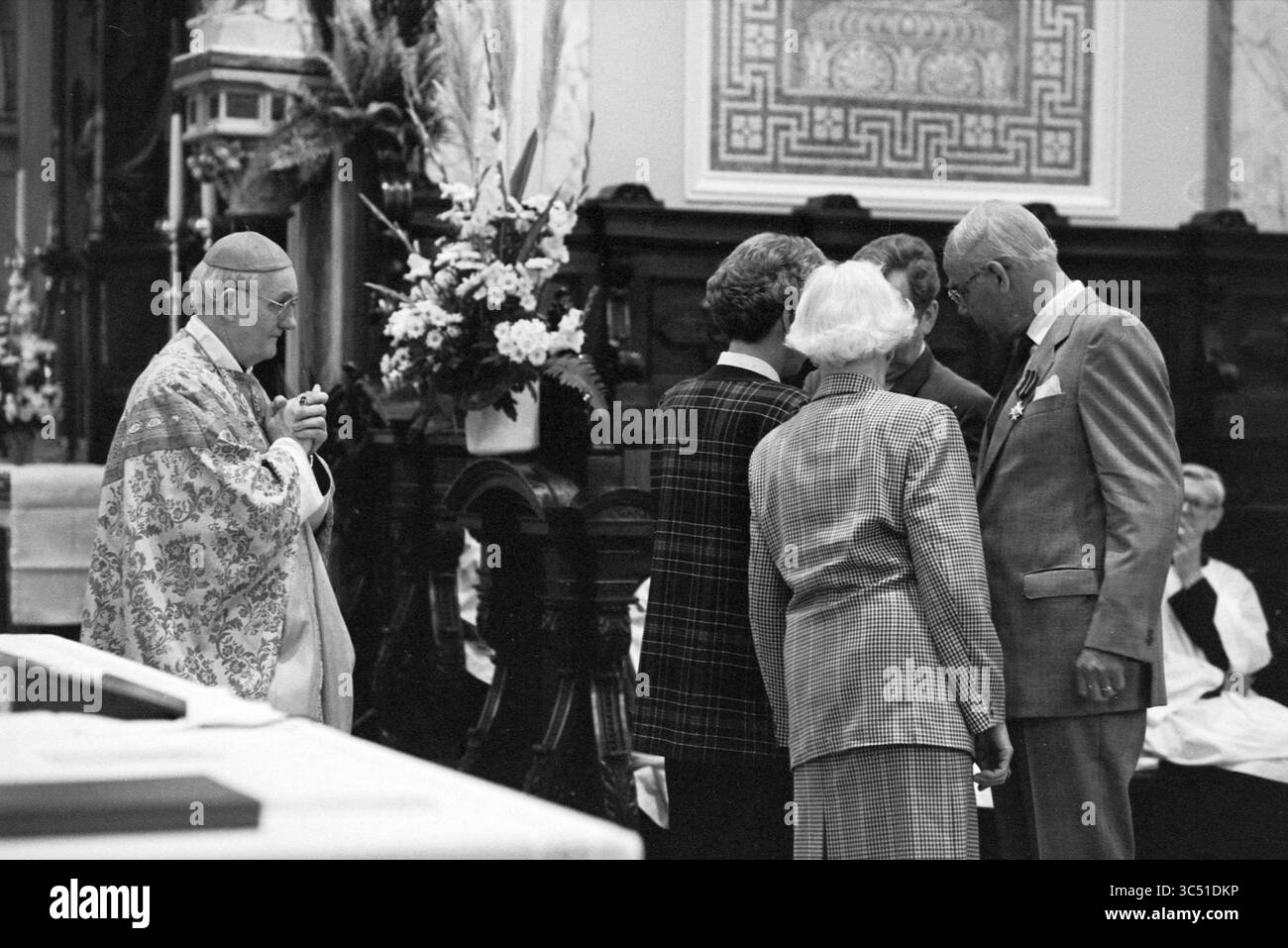Awards, Joseph Church, 15-05-1993 Whizgle News, Dutch Desk, Niederlande, 1950-2000 Es findet Eine religiöse Zeremonie statt, bei der ein Klerus in kunstvollen Gewändern mit einer kleinen Gruppe von Teilnehmern, darunter ein Paar in formeller Kleidung, interagiert. Die Umgebung bietet komplexe architektonische Details und Blumenarrangements, die eine feierliche Atmosphäre schaffen. Stockfoto