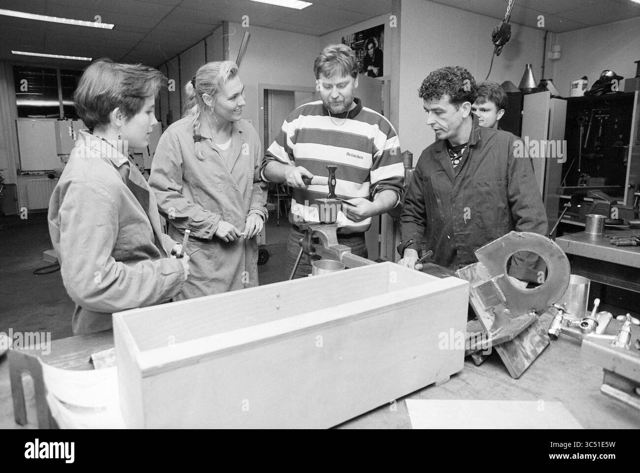 Arie Kuiper + Studenten C. Berufsausbildung, 01-11-1993 Whizgle News, Dutch Desk, Niederlande, 1950-2000 Eine Gruppe von vier Personen nimmt an einem praxisorientierten Workshop Teil und arbeitet an einem Projekt an einer Werkbank zusammen. Zwei Teilnehmer beobachten genau, wie eine dritte Person die Verwendung eines Tools demonstriert, während die vierte Person aufmerksam zuhört. Der Arbeitsbereich ist mit verschiedenen Werkzeugen und Materialien gefüllt, die eine praktische Lernumgebung darstellen. Stockfoto