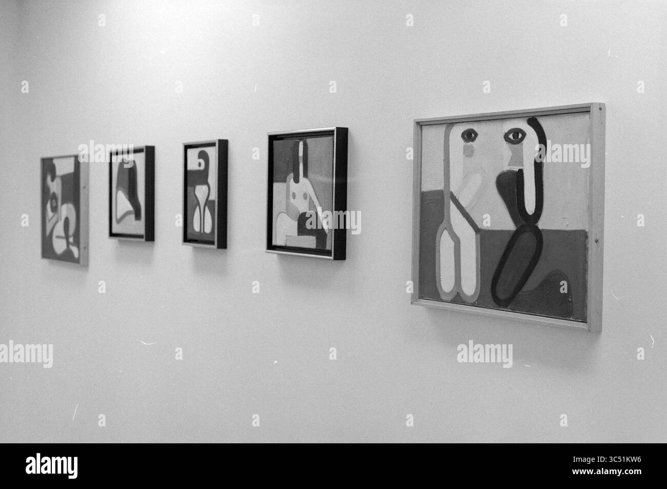Gallery Hakketak, 18-12-1992 Whizgle News, Dutch Desk, Niederlande, 1950-2000 Eine Reihe abstrakter Kunstwerke, die auf einer Wand gezeigt werden, mit geometrischen Formen und stilisierten Figuren in verschiedenen monochromatischen Tönen, die den Zuschauer zur Interpretation ihrer visuellen Erzählungen einladen. Stockfoto