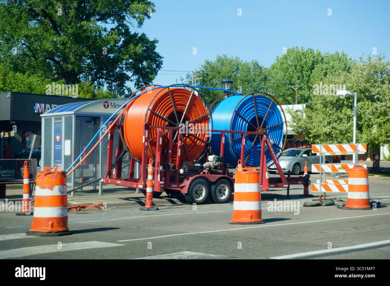 Zwei große Rollen mit orangefarbenen und blauen Kabelkanälen, die entlang der Straße verlegt werden können und das Elektrokabel halten. St. Paul Minnesota MN USA Stockfoto