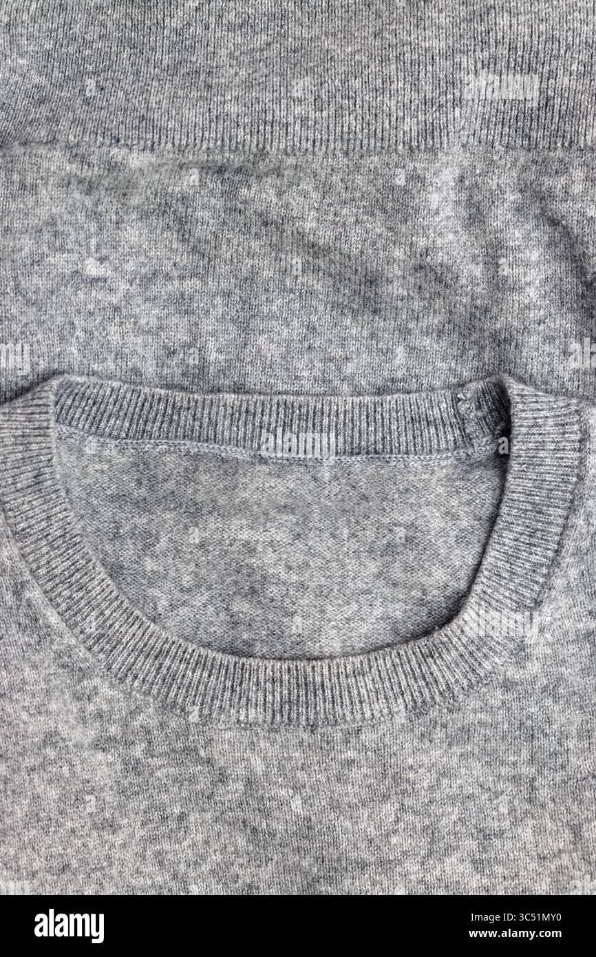 Eine detaillierte Nahaufnahme eines grauen Strickmaterials mit Textur und Muster. Stockfoto