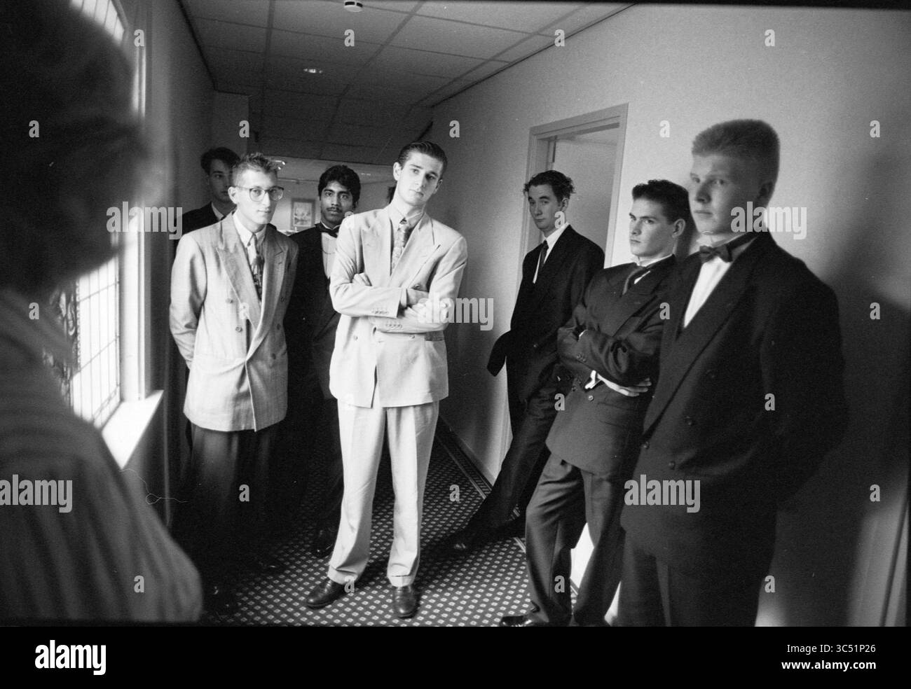 Students Lion d'Or, 02-09-1992 Whizgle News, Dutch Desk, Niederlande, 1950-2000 Eine Gruppe junger Männer in stilvollen Anzügen steht in einem schmalen Korridor und zeigt eine Mischung aus selbstbewussten und kontemplativen Ausdrücken. Die Wahl der Mode spiegelt einen formellen Anlass wider, während die Umgebung einen Hauch von Vorfreude verleiht. Stockfoto