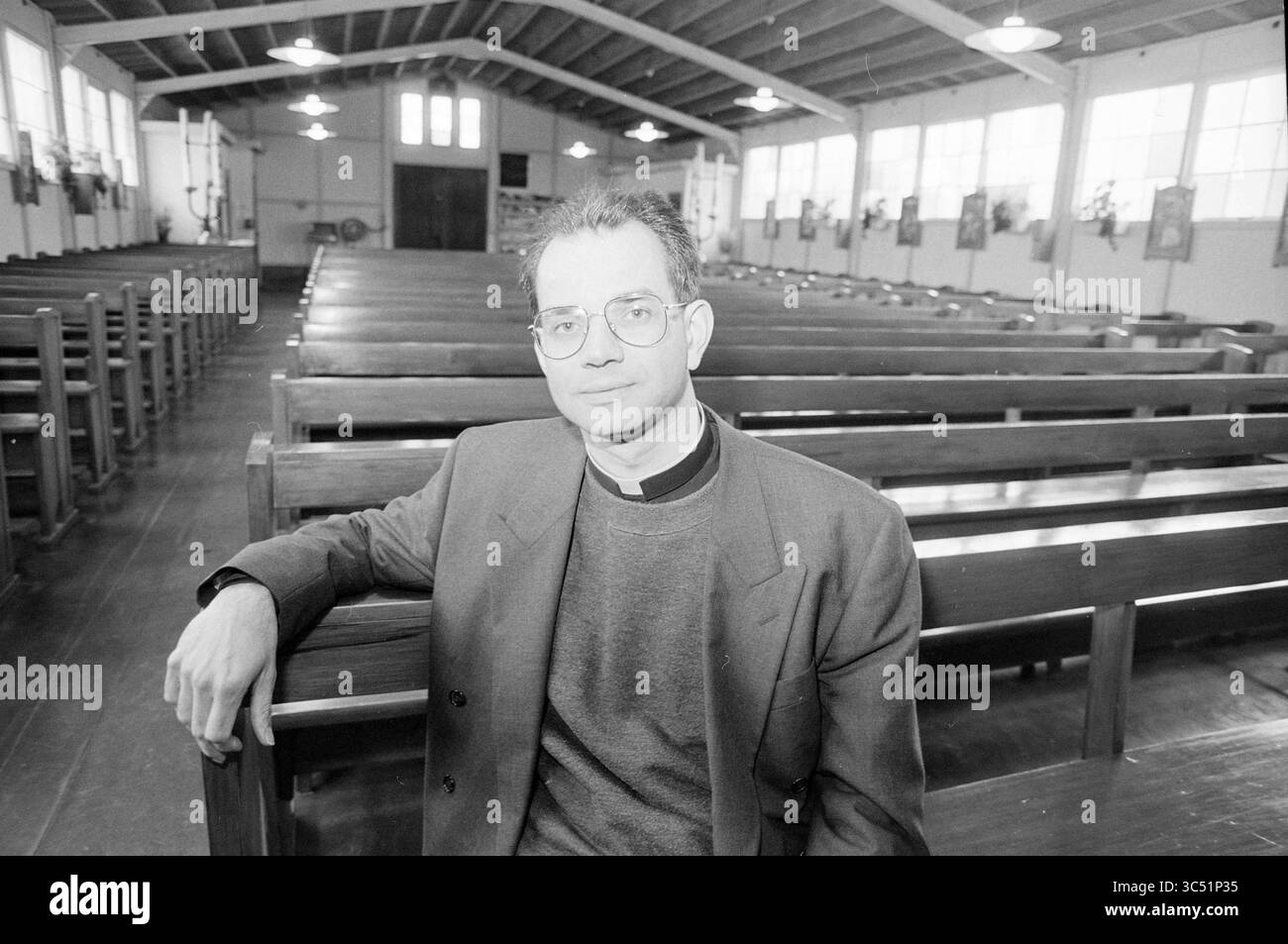 Pastor Dohmen, B'wijk, Beverwijk, Niederlande, 06-04-1994 Whizgle News, Dutch Desk, Niederlande, 1950-2000 Ein Geistlicher sitzt in einer spärlich eingerichteten Kirche, umgeben von leeren Holzbänken, und blickt ruhig in die Ferne. Das Innere verfügt über hohe Decken und große Fenster, die ein Gefühl von Offenheit für den Raum vermitteln. Stockfoto