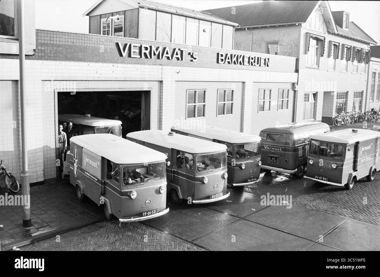 Vermaat's Bäckereien mit Lieferwagen, Paul Krugerkade 31, Haarlem, Paul Krugerkade, Niederlande Whizgle News, Dutch Desk, Niederlande, 1950-2000 Eine Reihe von Lieferwagen steht vor einer Bäckerei, wobei ein Lieferwagen teilweise aus dem Gebäude herauskommt. Die Szene zeigt einen hektischen Moment, während Mitarbeiter ihre Aufgaben erfüllen, umgeben von Fahrrädern und anderen Fahrzeugen in einer geschäftigen städtischen Umgebung. Die Beschilderung der Bäckerei ist gut sichtbar auf dem Gebäude angebracht. Stockfoto